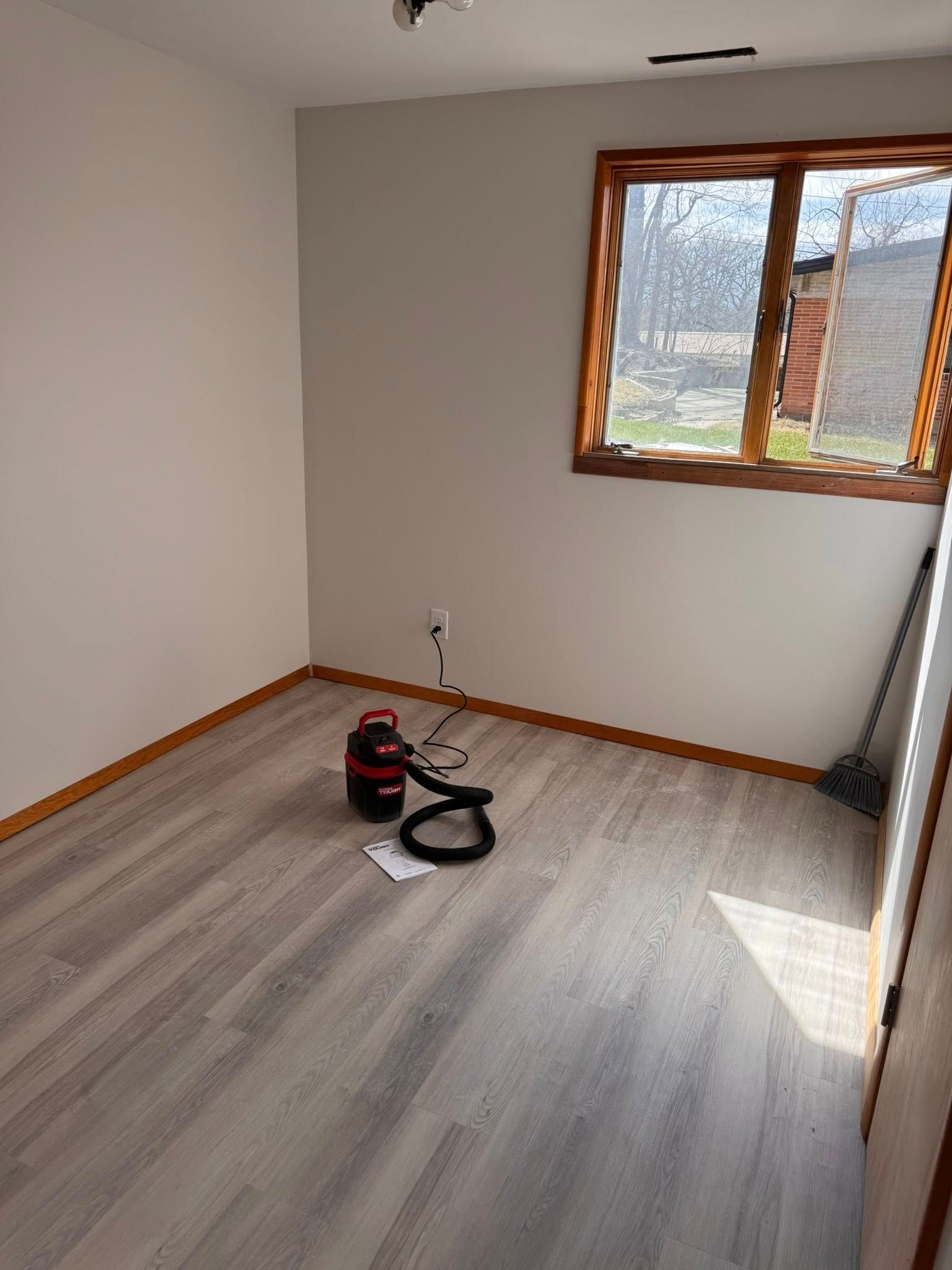 A room with a vacuum cleaner and a broom on the floor.