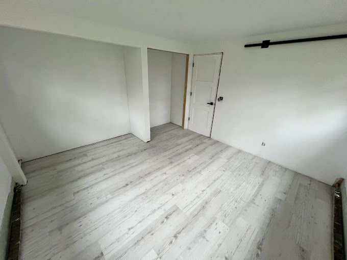 An empty room with a wooden floor and white walls.