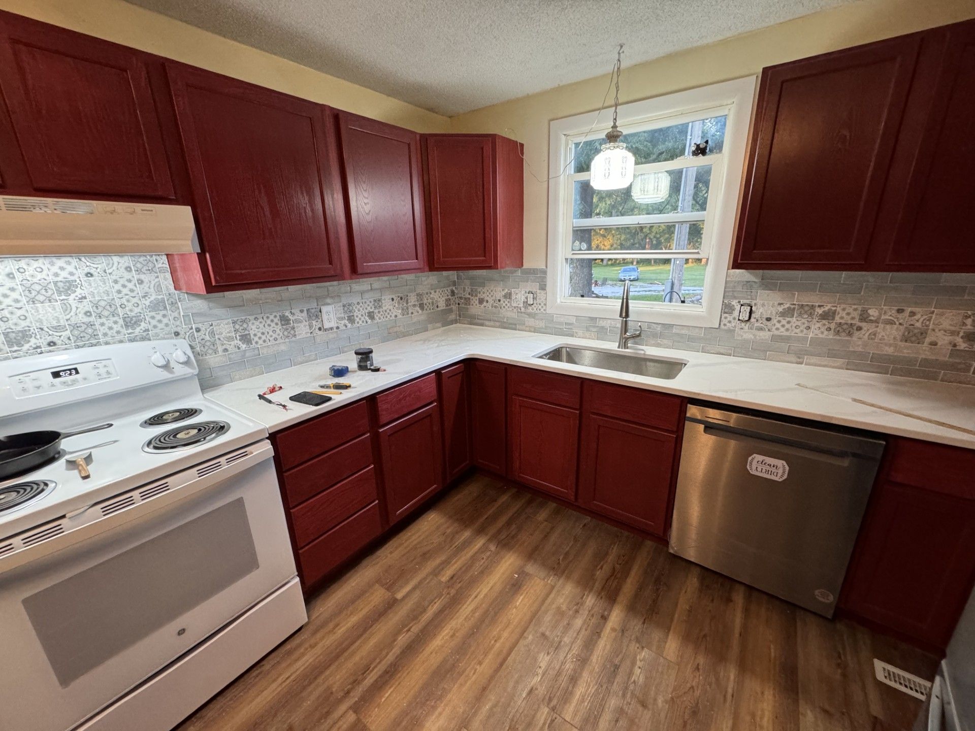 A man is measuring a counter in a kitchen under construction.