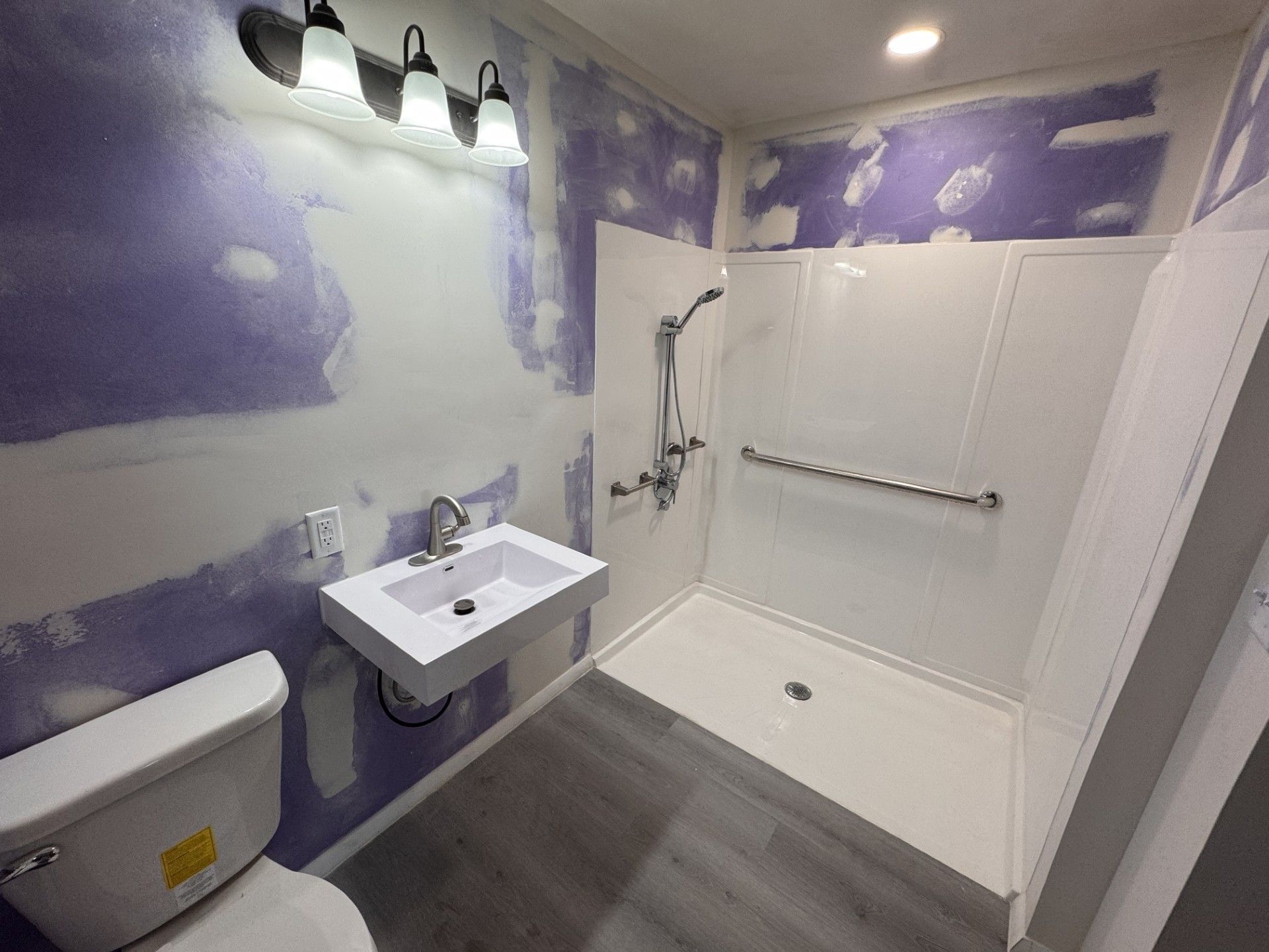 A bathroom with a toilet , sink and mirror.