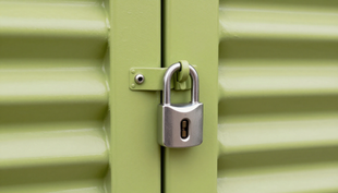 Close-up of a silver padlock securing a blue storage unit door with a metal latch.