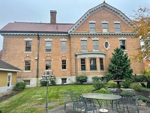 A large brick mansion with a garden and lawn in front