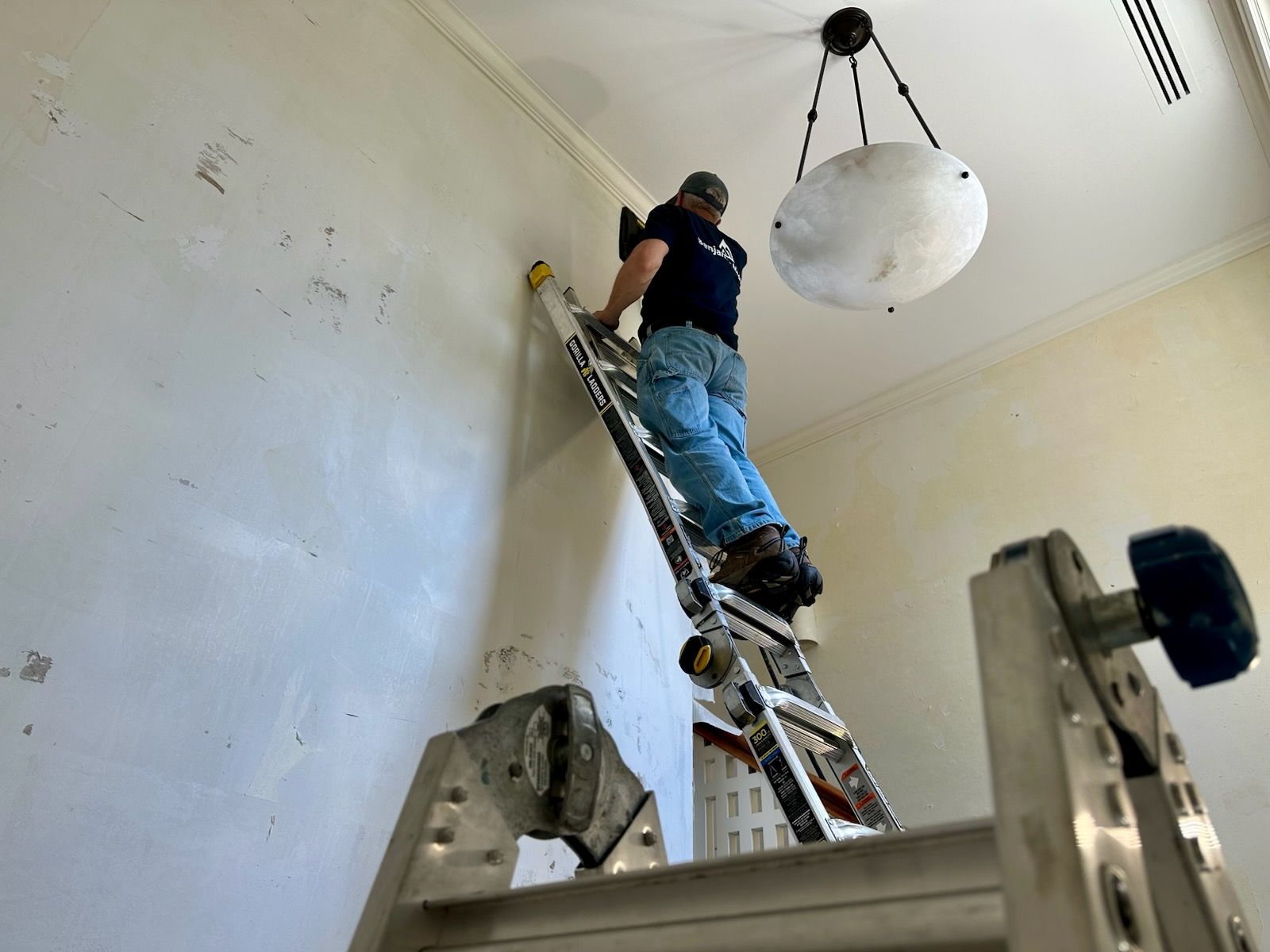 A person on a ladder scraping walls