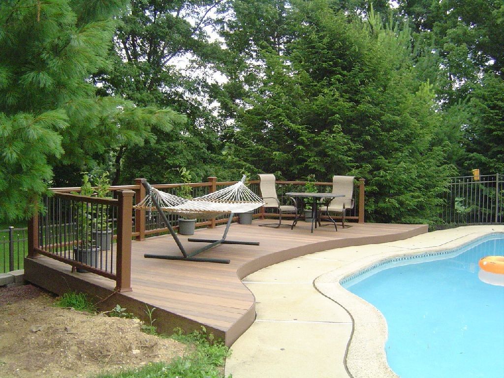 A deck with a table and chairs next to a swimming pool