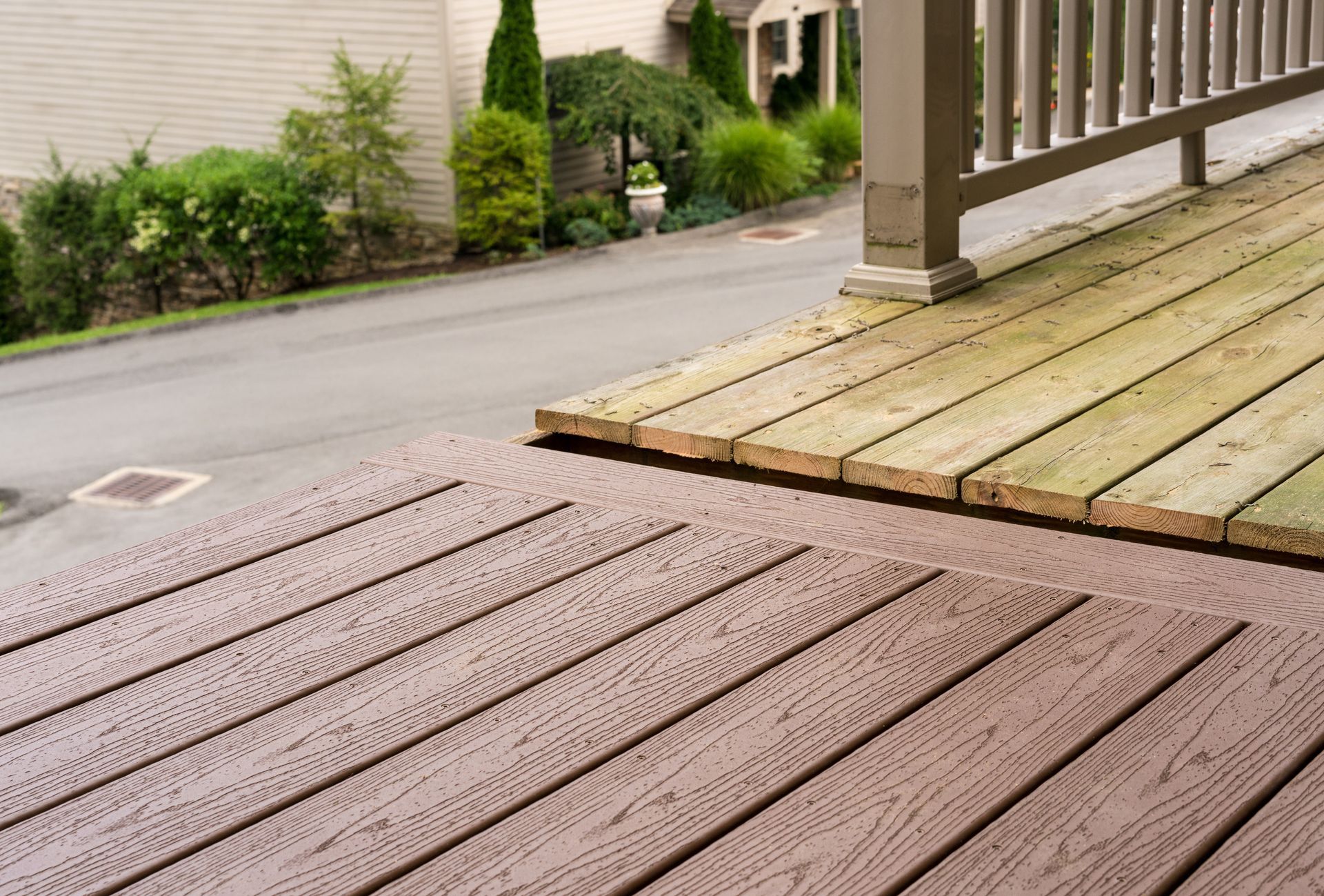 A wooden deck with a railing and a house in the background.