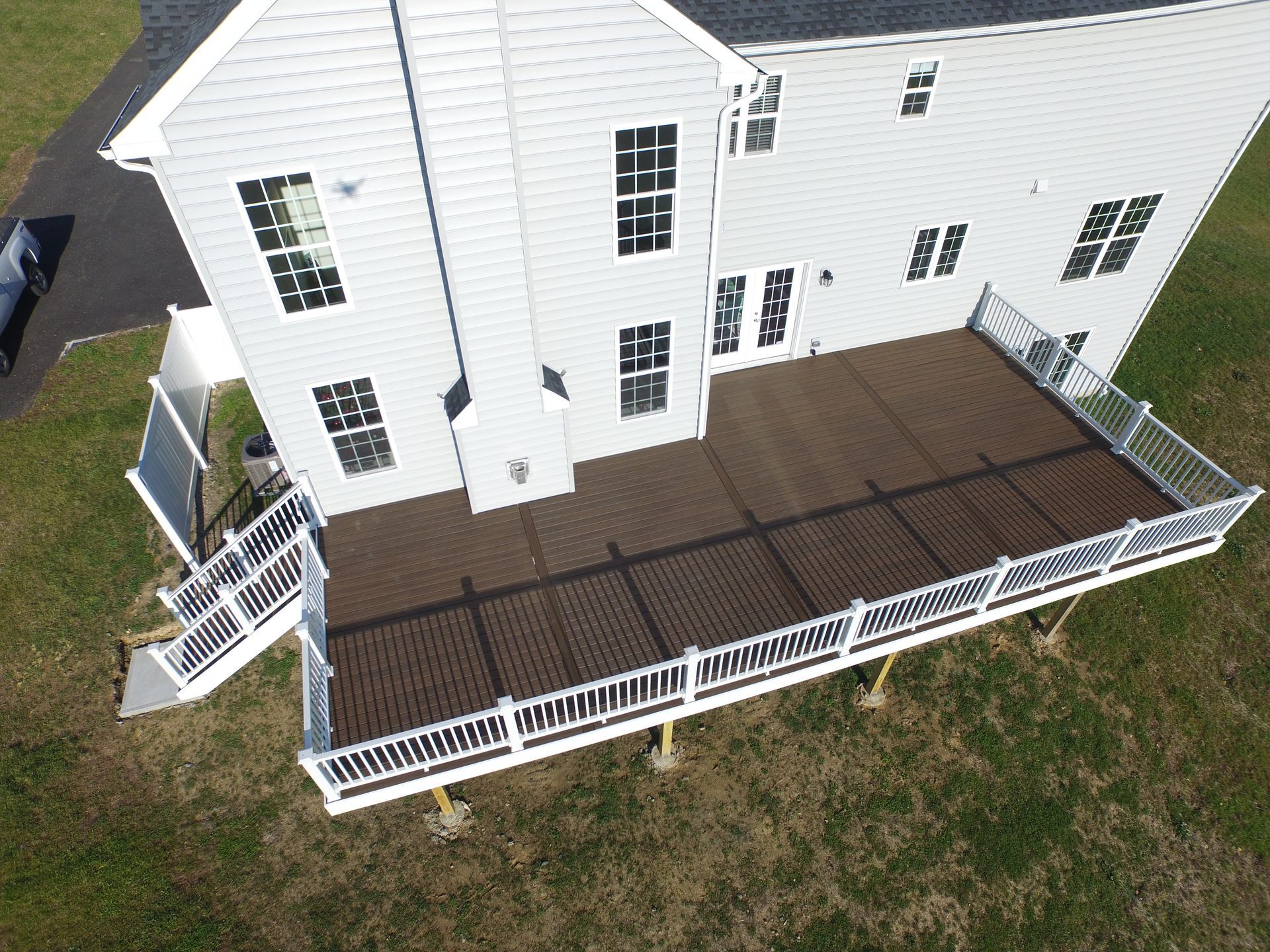 An aerial view of a large white house with a large deck.
