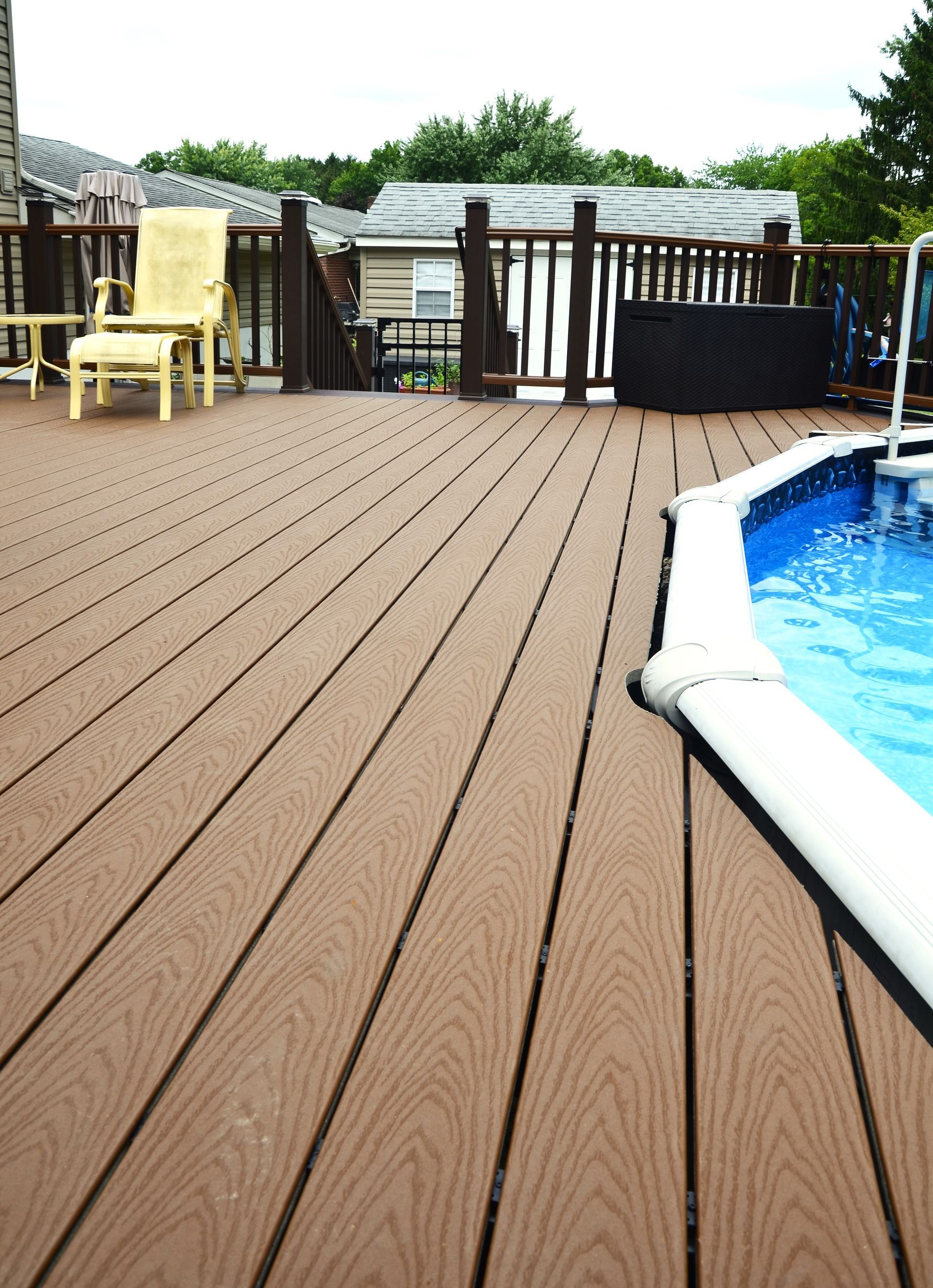 A wooden deck with a swimming pool in the background