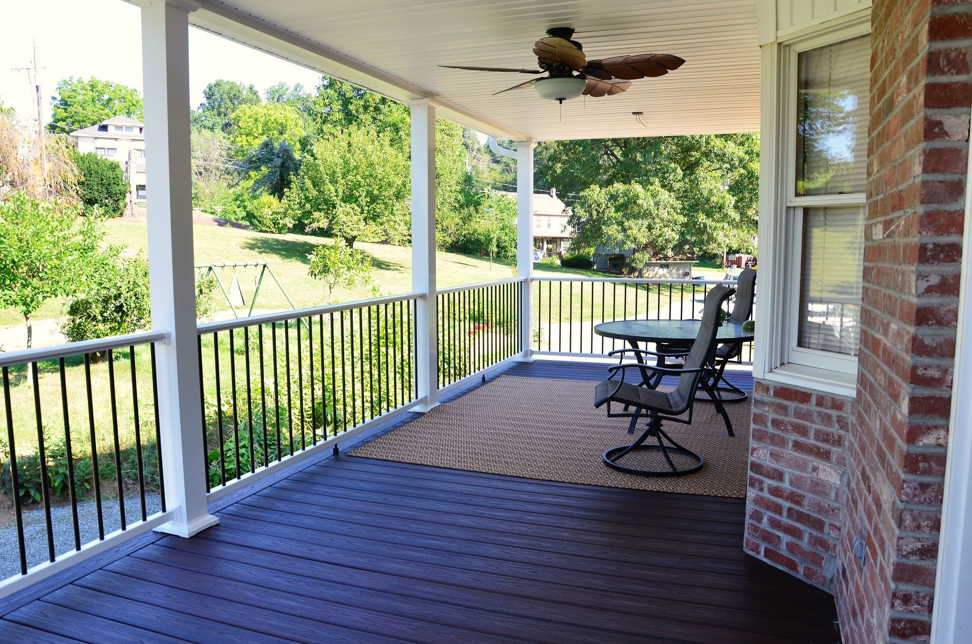 A porch with a table and chairs and a ceiling fan