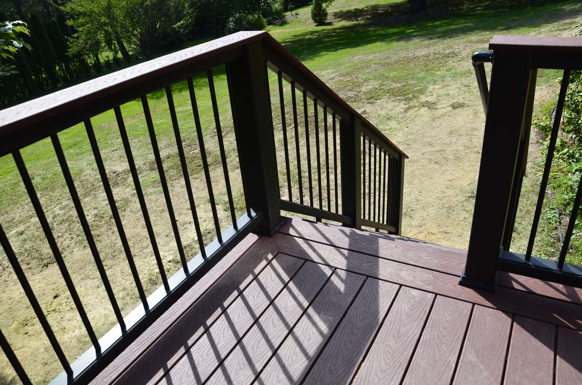 A wooden deck with stairs and a black railing