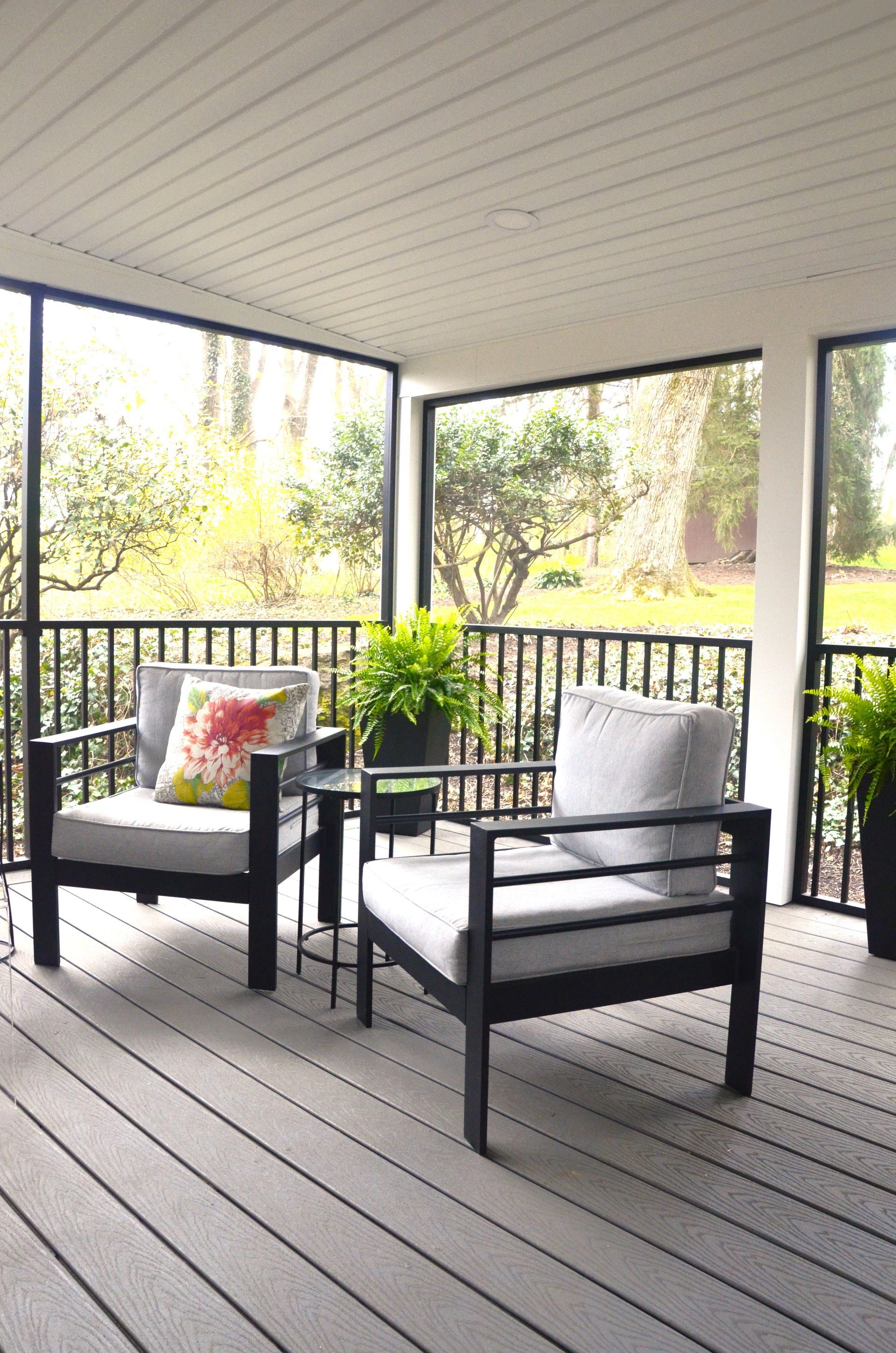 A screened in porch with two chairs and a table