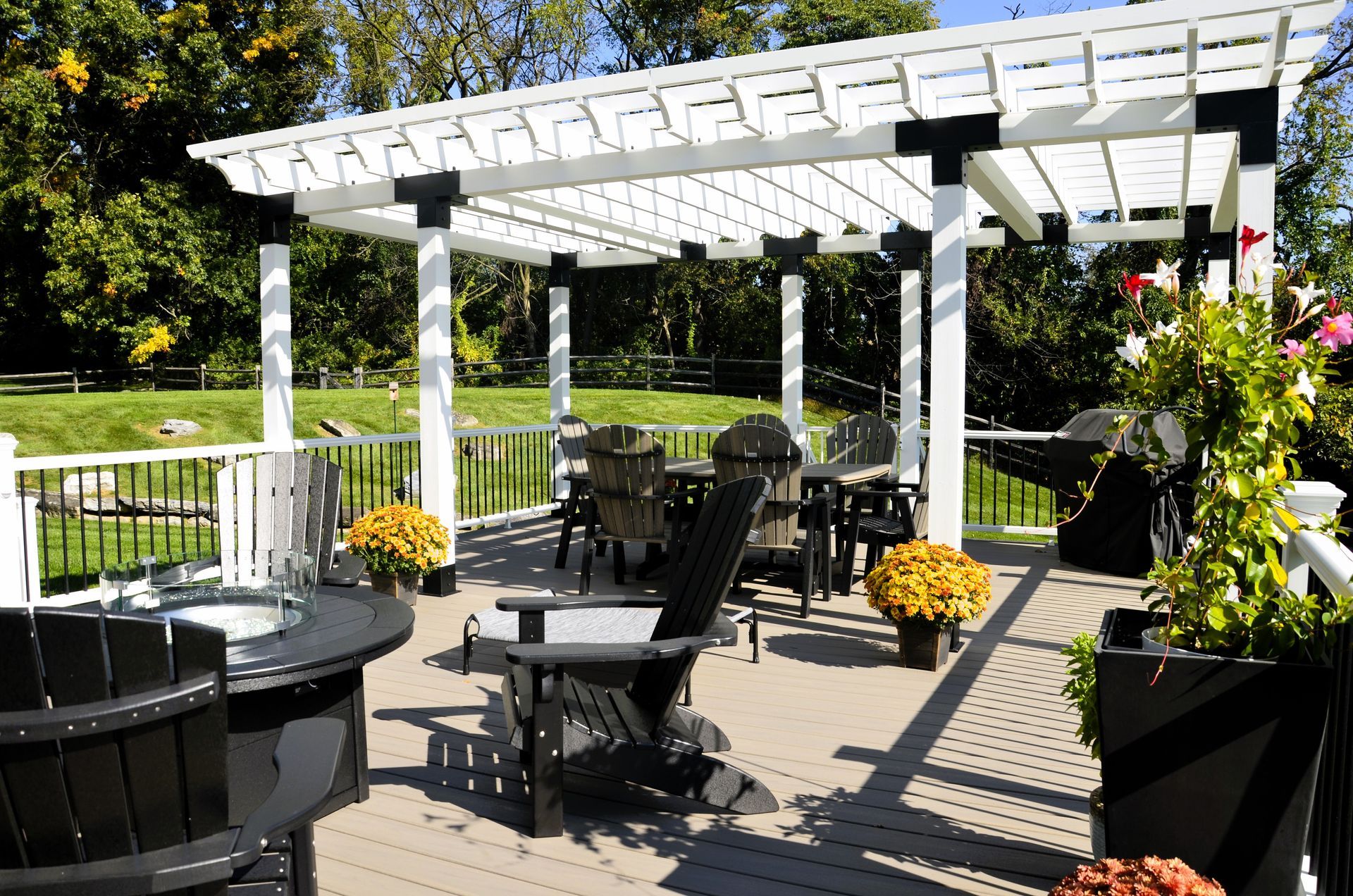 A deck with chairs and a table under a pergola