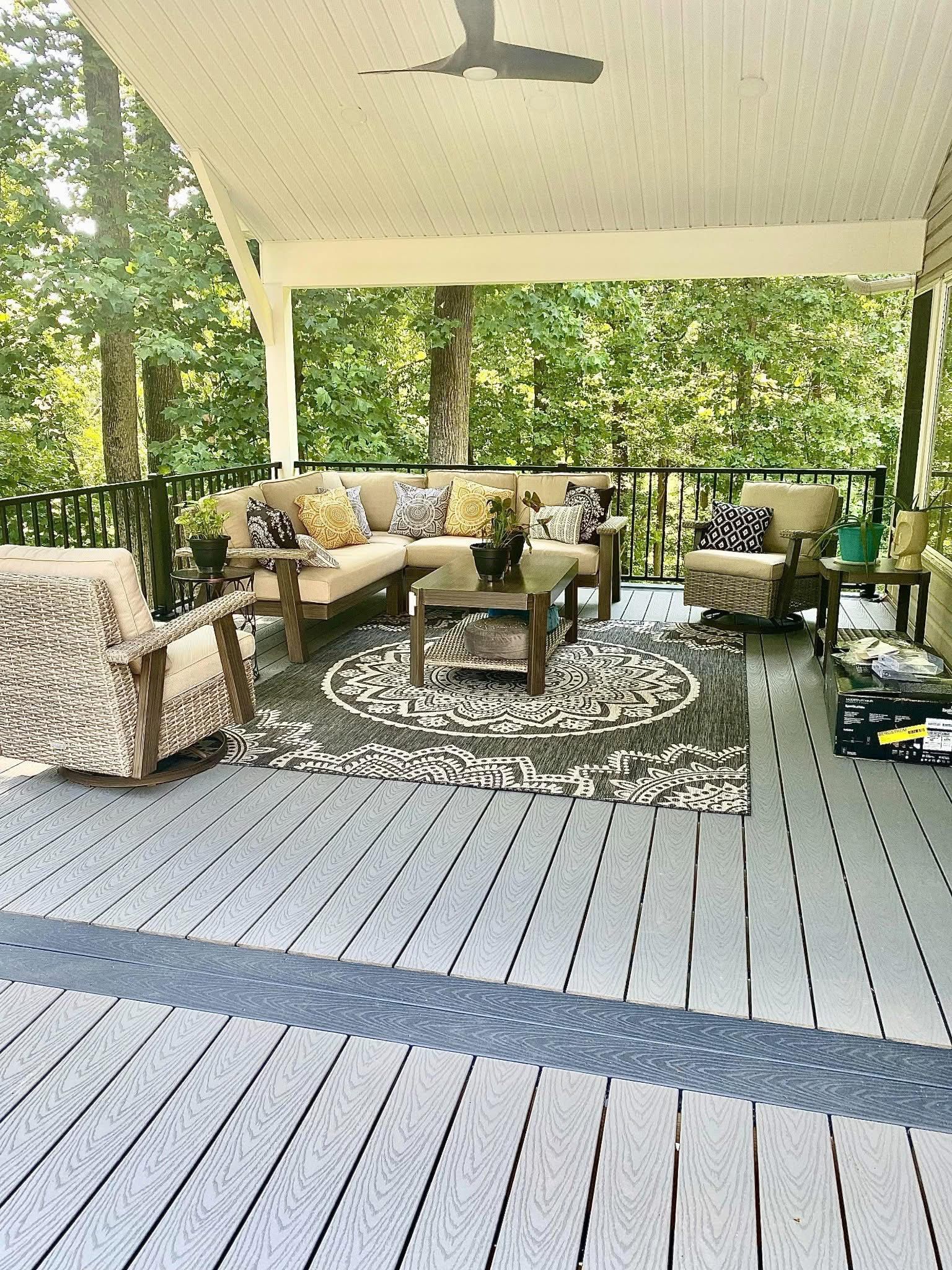 A porch with a couch , chairs , and a ceiling fan.