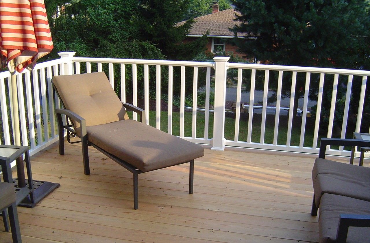 A deck with chairs and flowers under a pergola