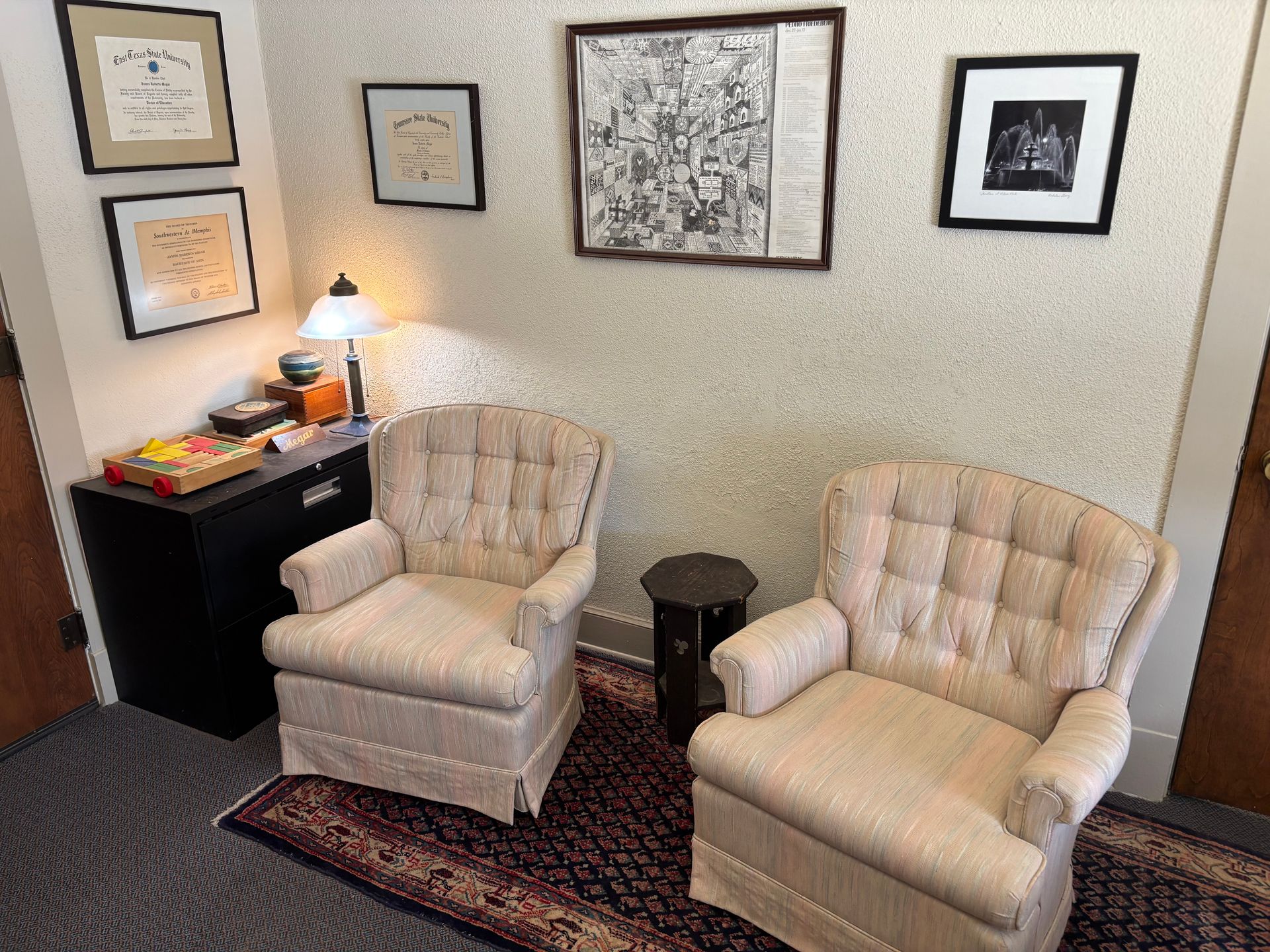 Two chairs are sitting in a room with pictures on the wall.