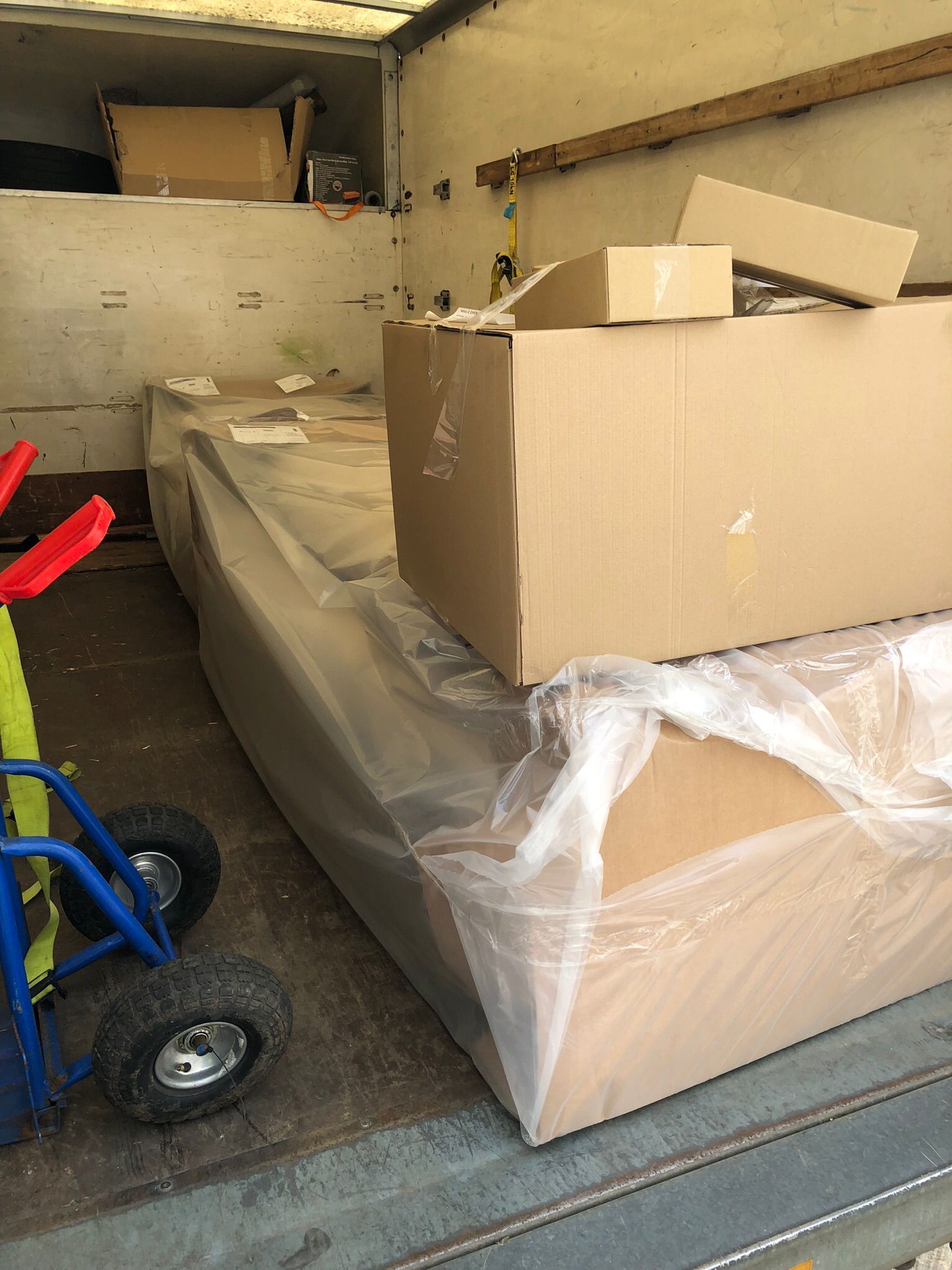 Packed cardboard boxes and furniture wrapped in plastic inside a moving van