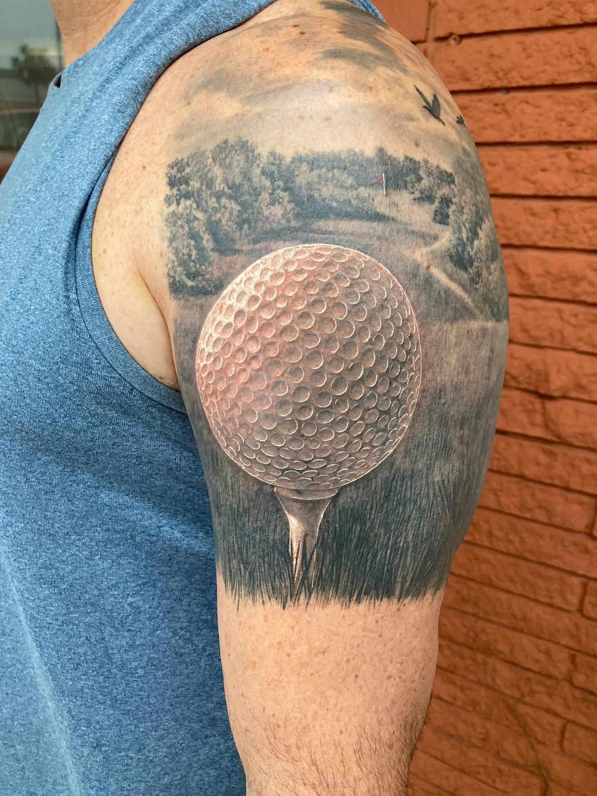 A man has a tattoo of a golf ball on his arm.
