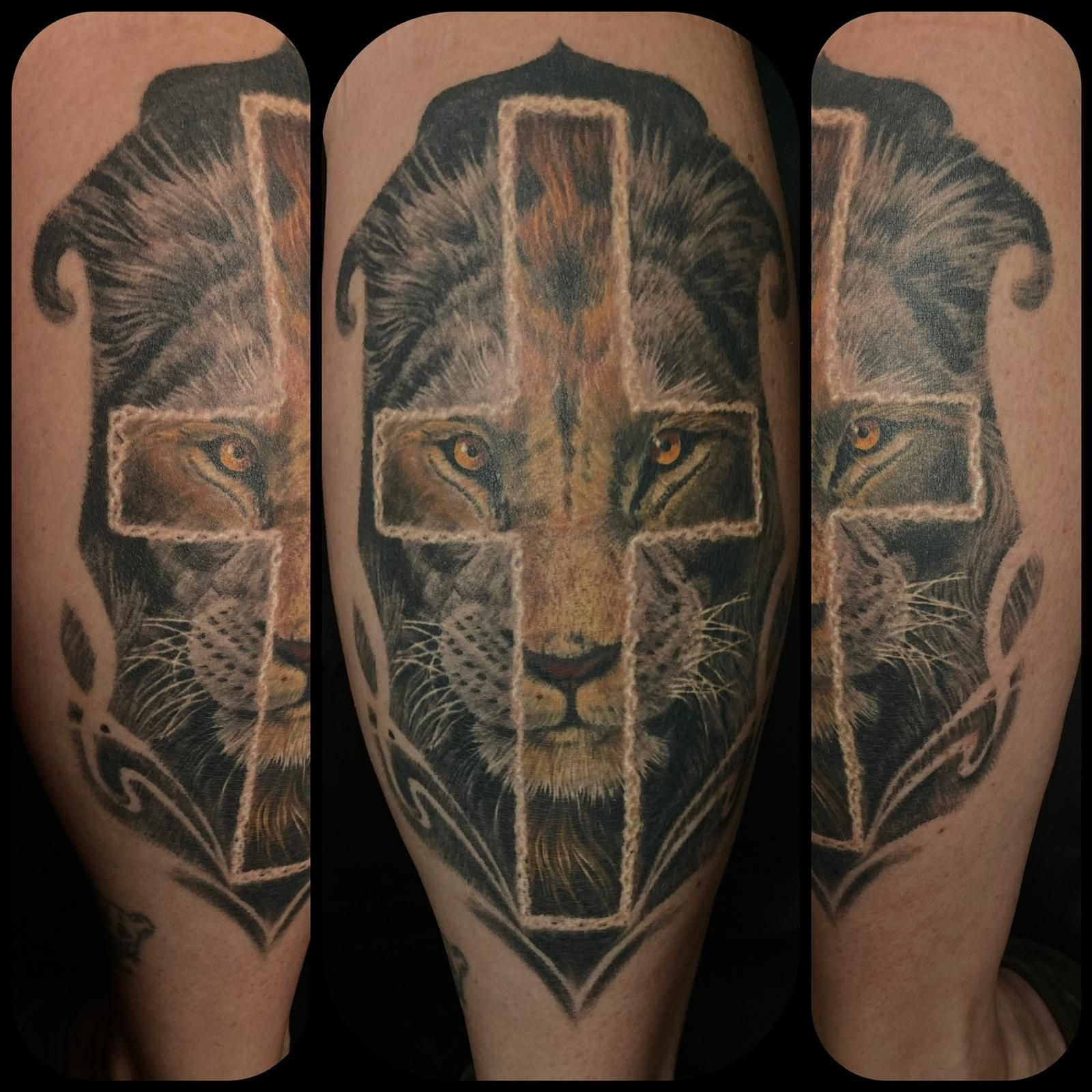 A tattoo of a lion and a cross on a leg