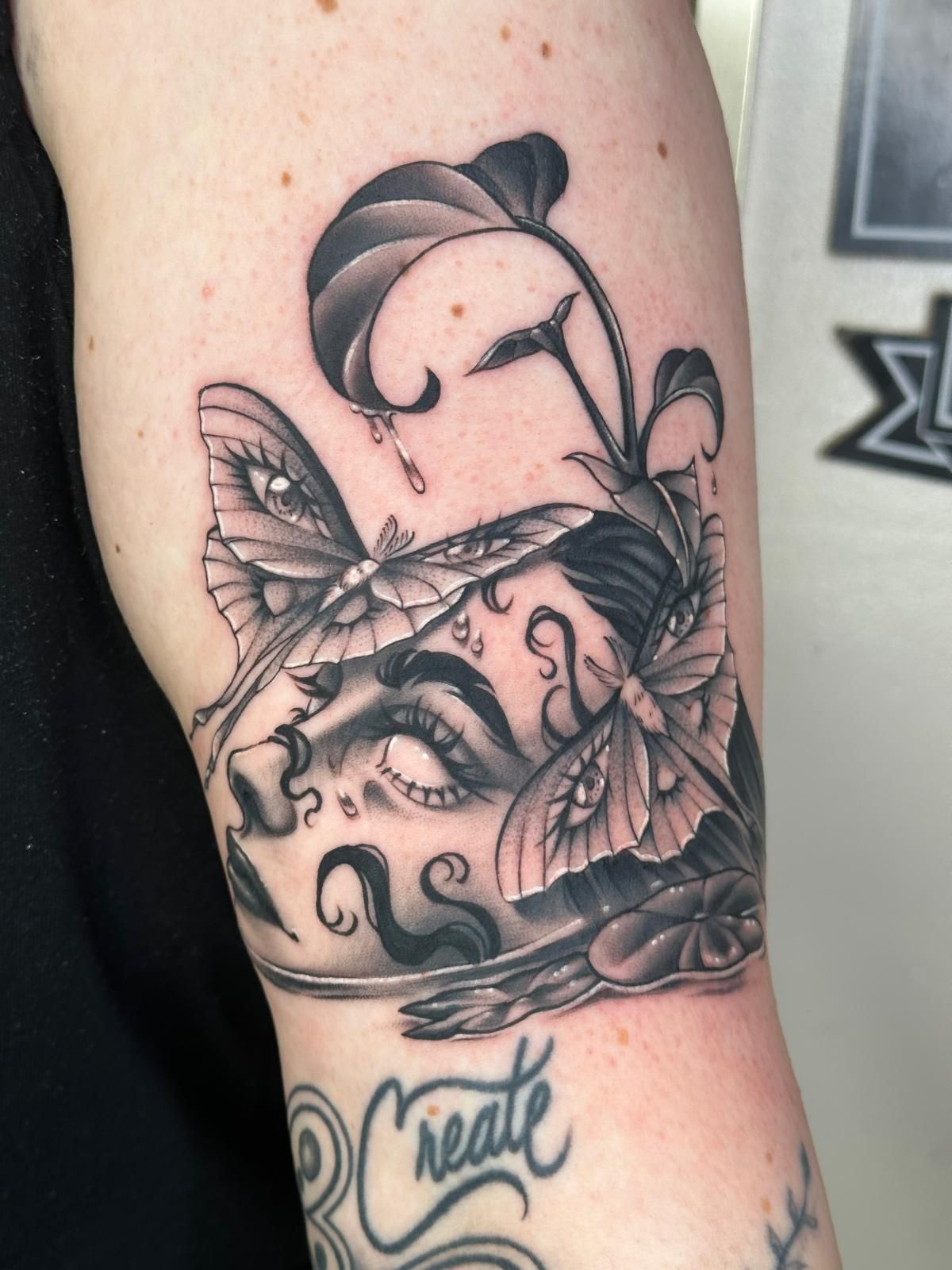 A woman has a tattoo on her arm that says create