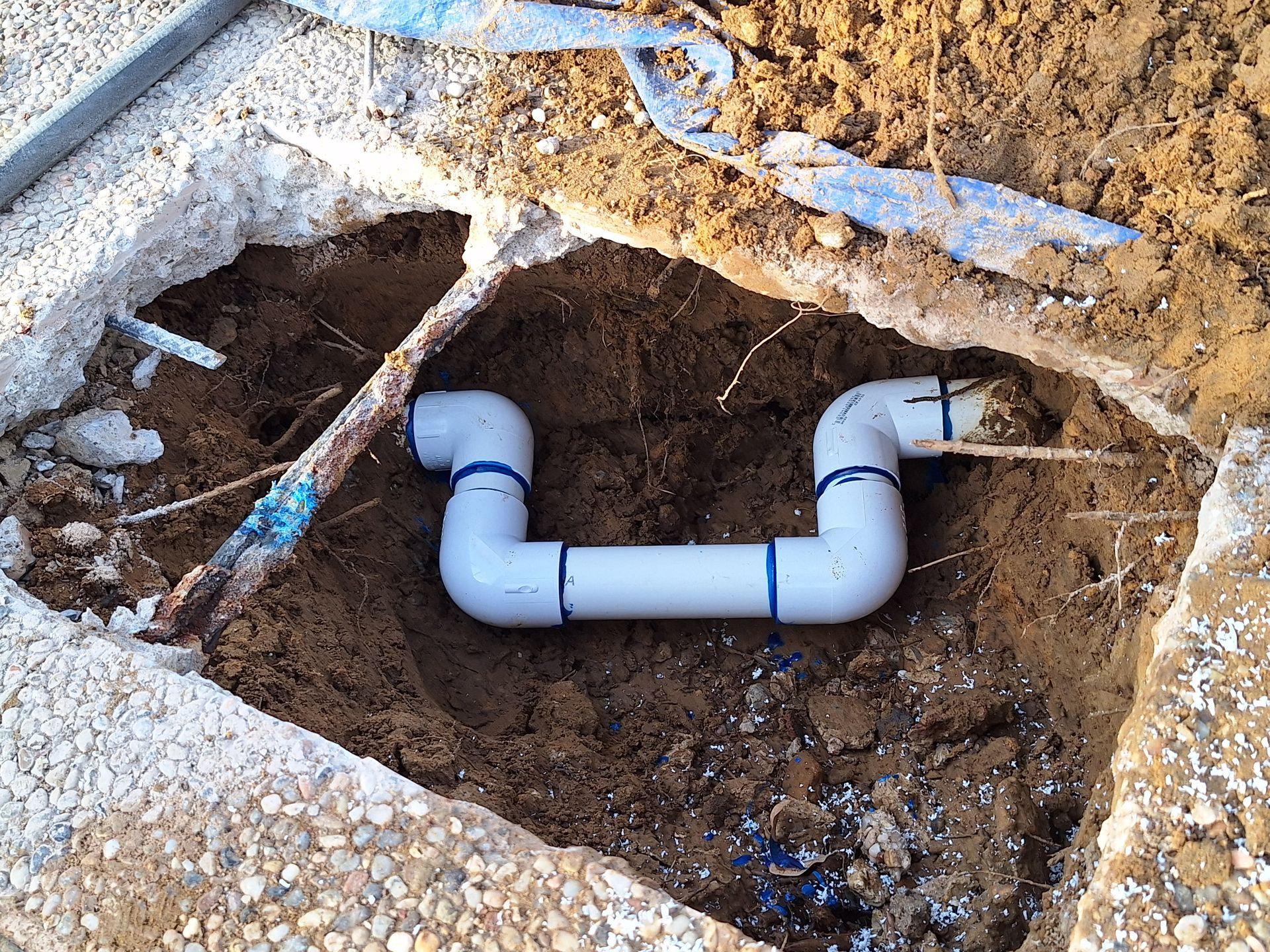 A completed plumbing repair on a pool, under the pool's concrete deck.