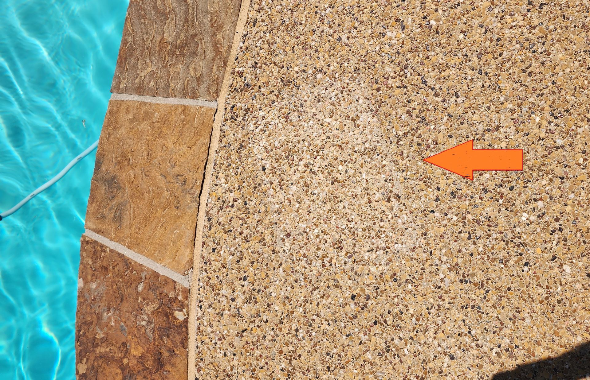 An exposed aggregate concrete patch after a pool plumbing repair.