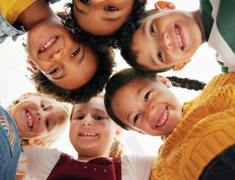 A group of children are standing in a circle and smiling