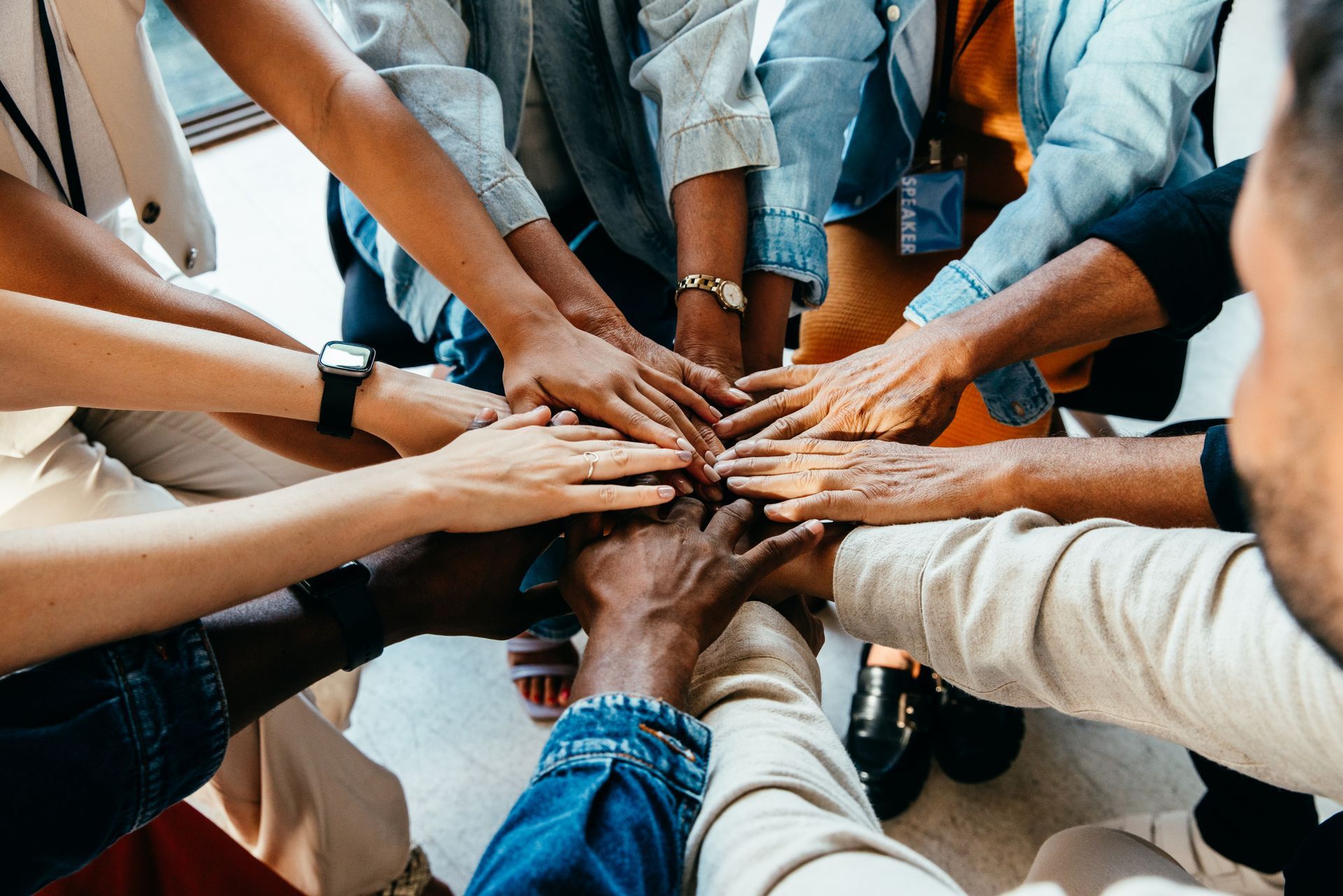 Hands of diverse people joined together in a team huddle.