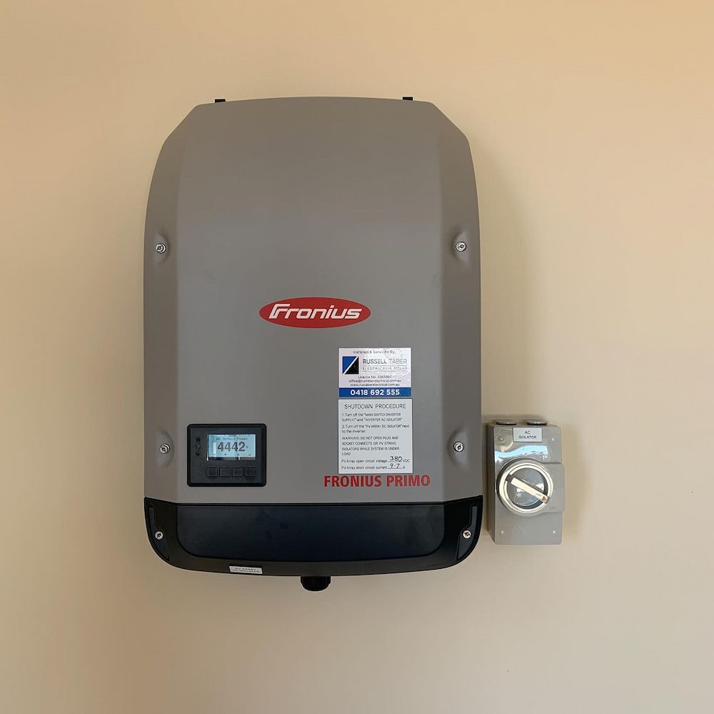 A Solar Panel Inverter is Mounted on a Wall Next to a Switch — Russell Taber Electrical & Solar in Lake Albert, NSW