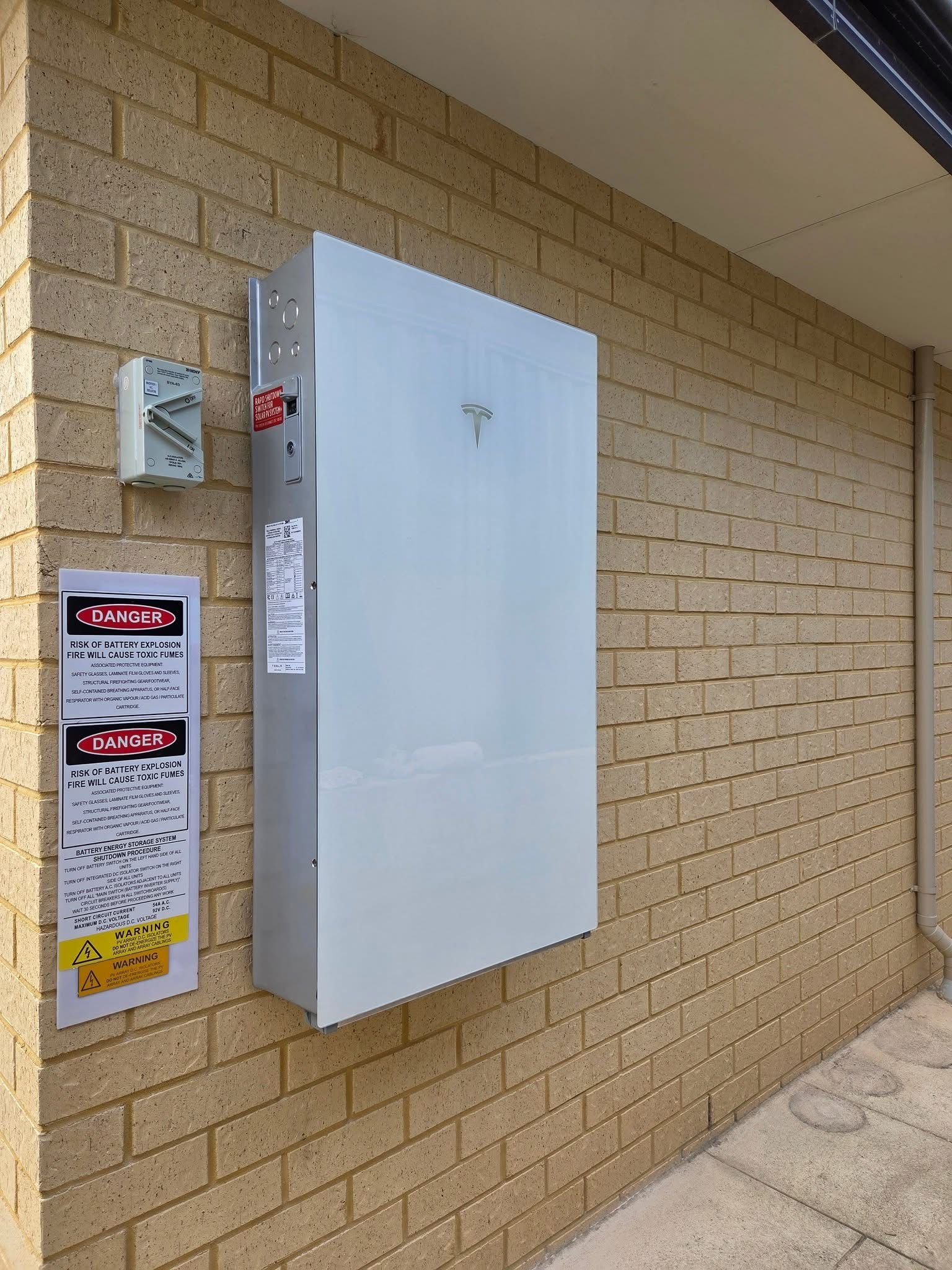 White solar battery mounted on a brick wall next to an electrical meter — Russell Taber Electrical & Solar in Lake Albert, NSW 
