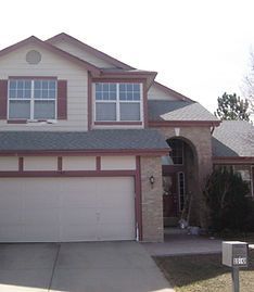 A two-story suburban house with a tan brick and siding exterior, a two-car garage, and a covered front entryway.