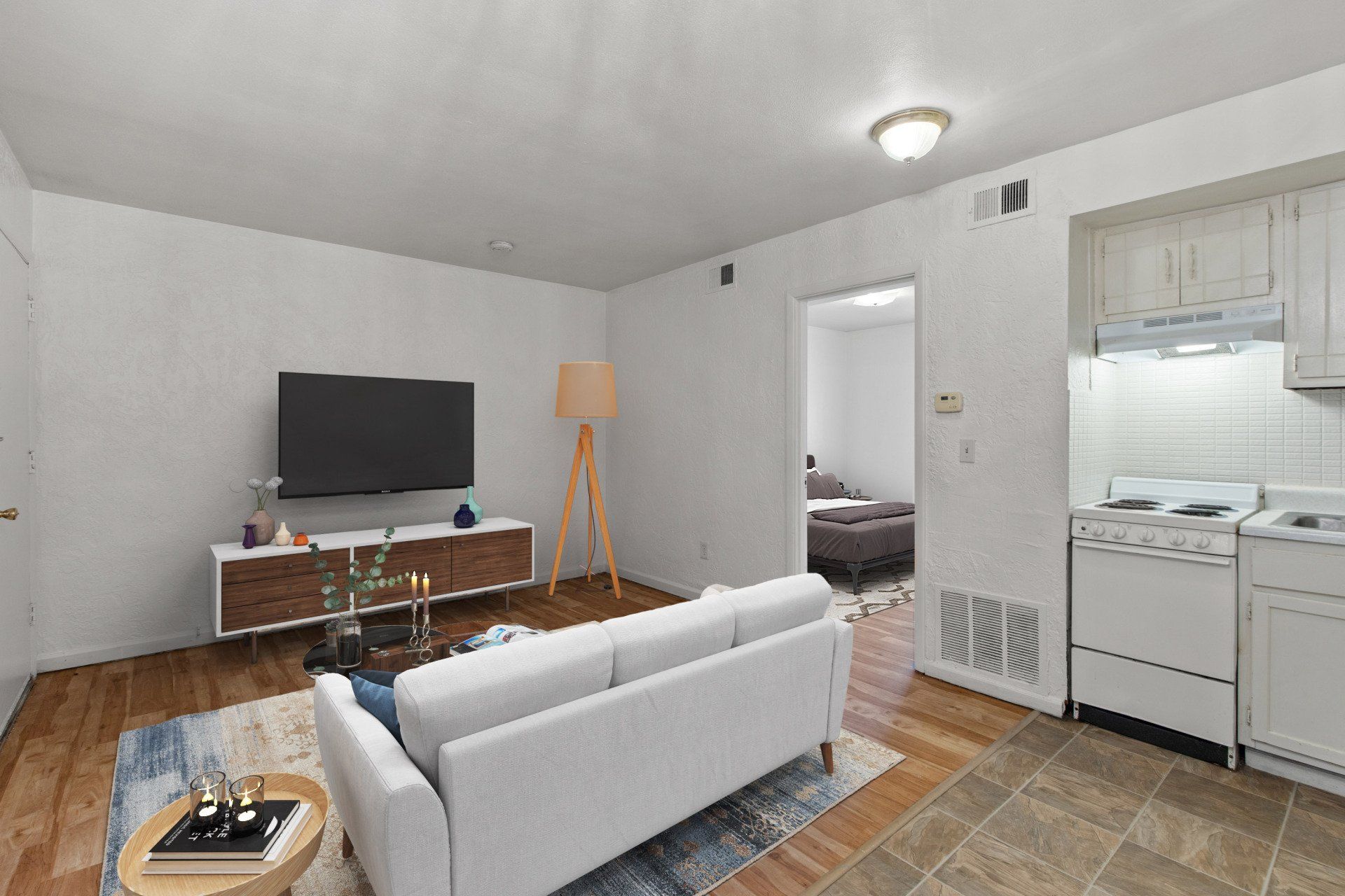Updated living room with view towards bedroom,  hardwood floor and window; and sofa, rug, and tv stand are for example only.