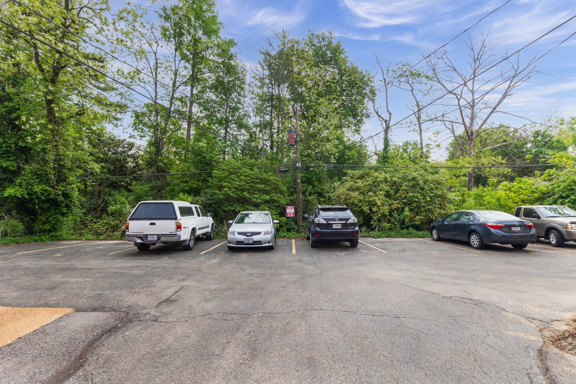 Exterior of Leslie Apartments parking lot surrounded by beautiful trees.