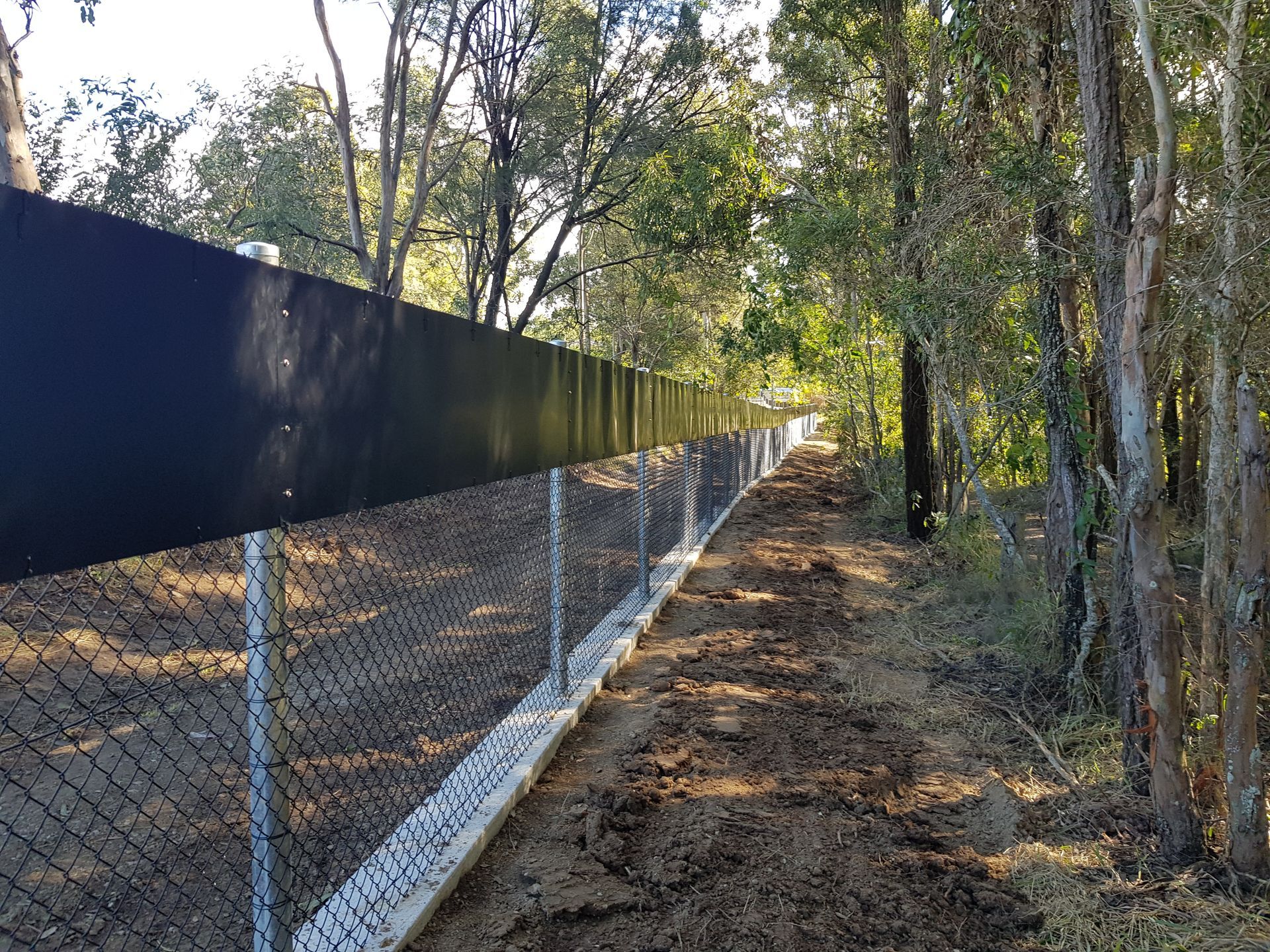 A Chain-link Fence Topped With a Black Privacy Screen Runs — PROFENCE AND RETAINING in Beecher, QLD