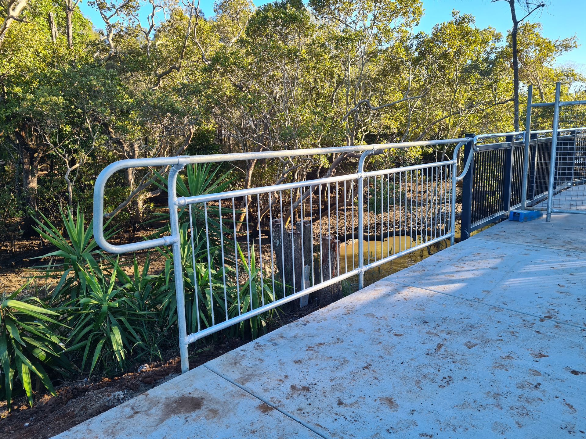A White Metal Railing Borders a Concrete Walkway — PROFENCE AND RETAINING in Beecher, QLD