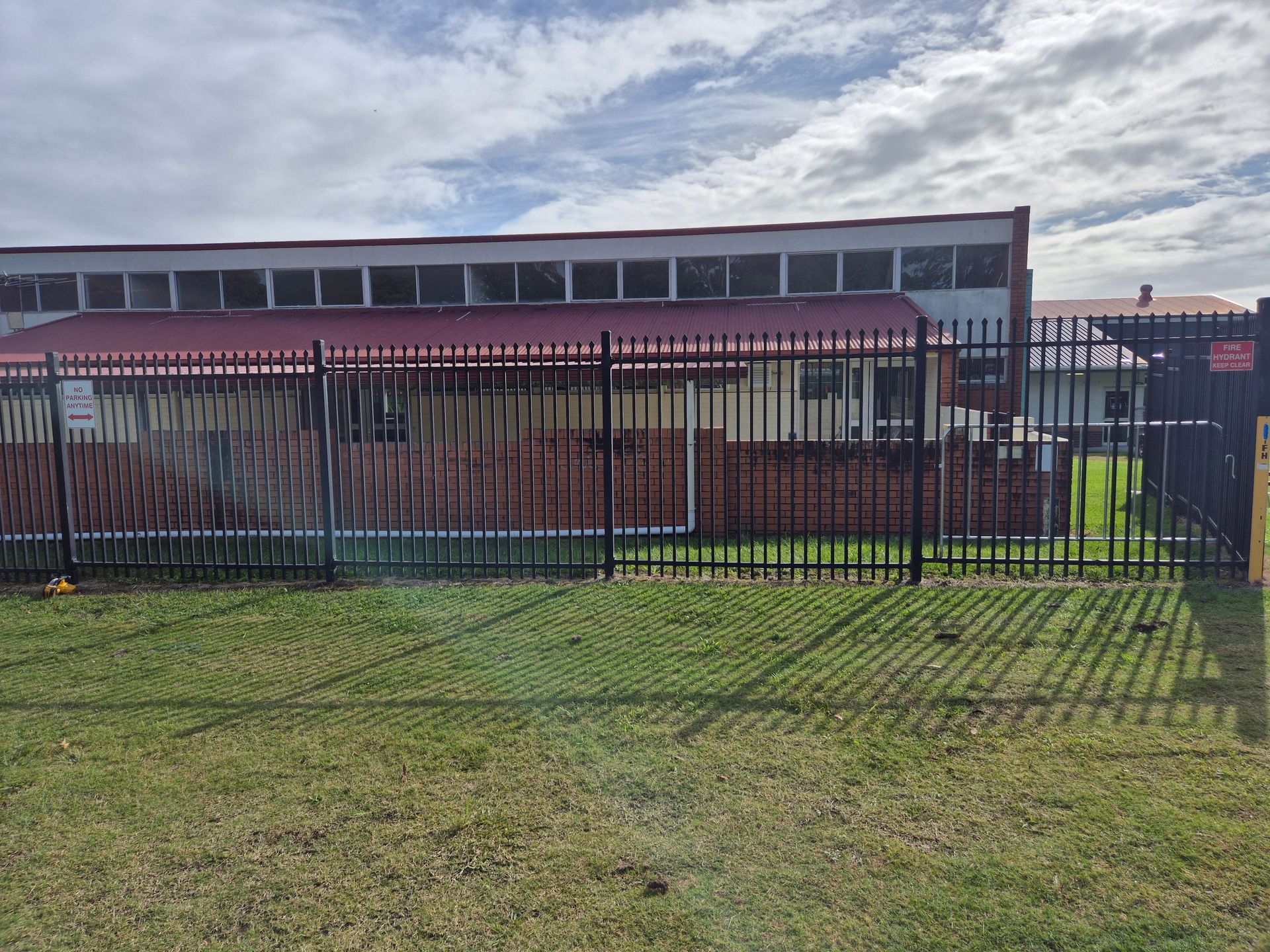 White vinyl fence with gate in a backyard, beside a building with gray siding, in sunlight — PROFENCE AND RETAINING in Beecher, QLD