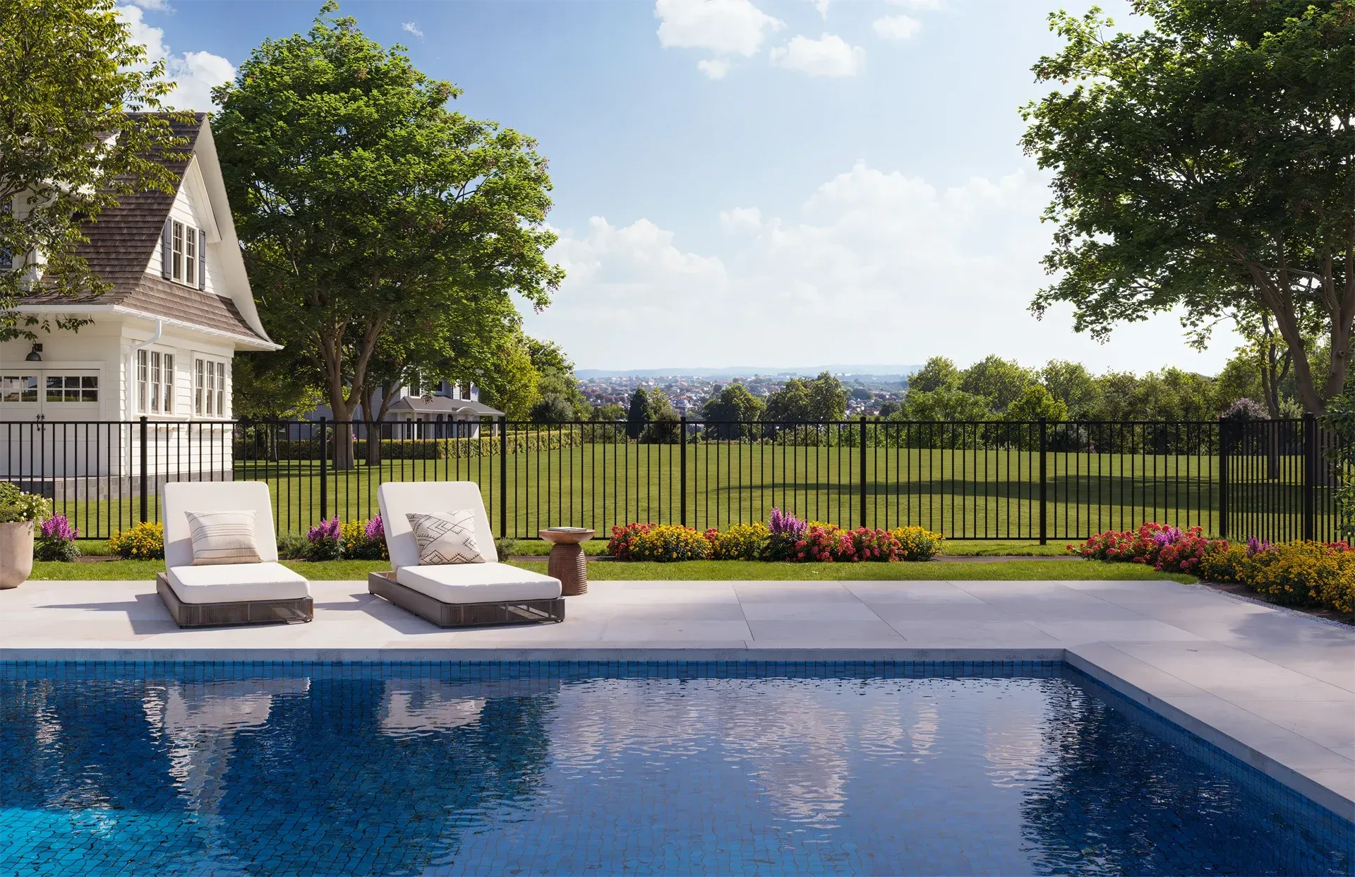 Swimming pool with lounge chairs, fenced yard, and white house on a sunny day.