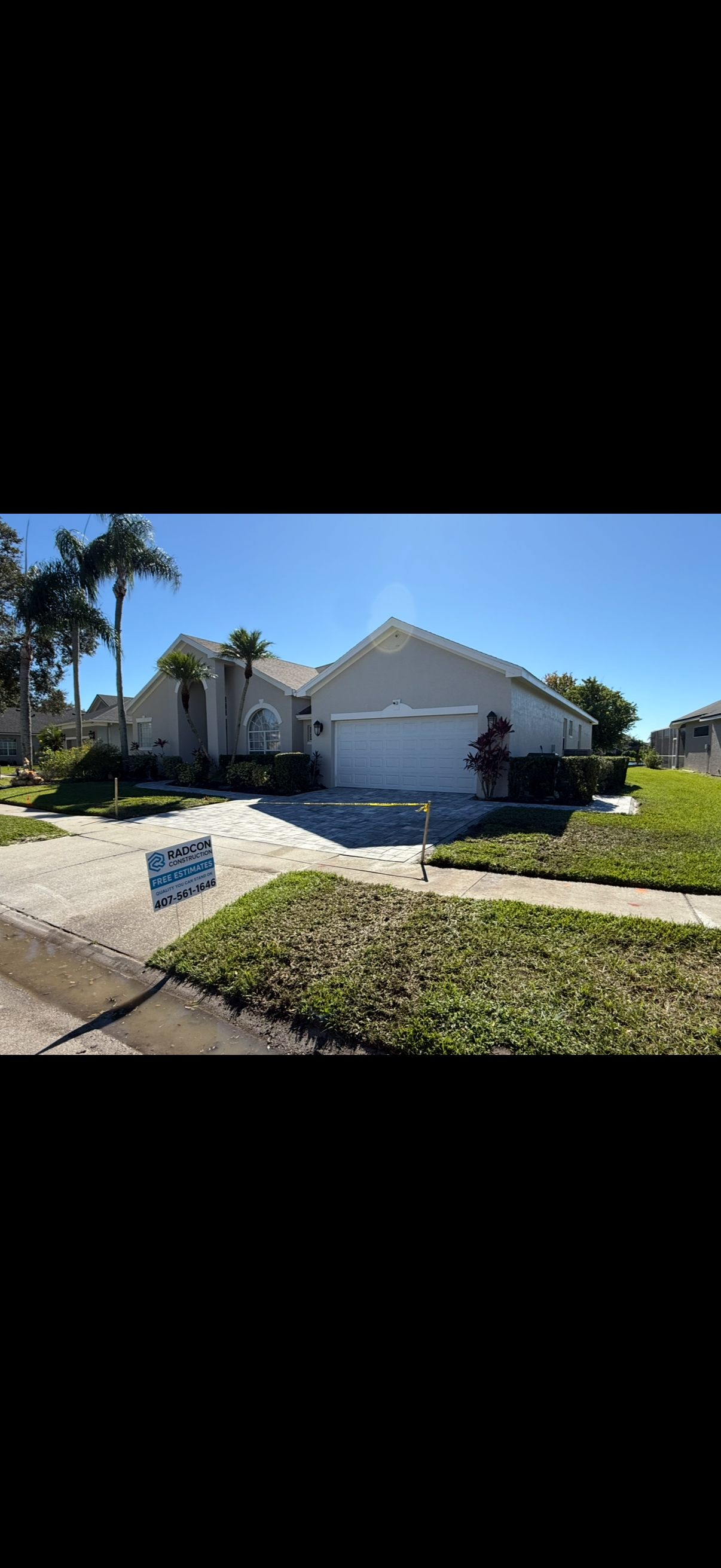A single-story house with a driveway and lawn under a clear blue sky.