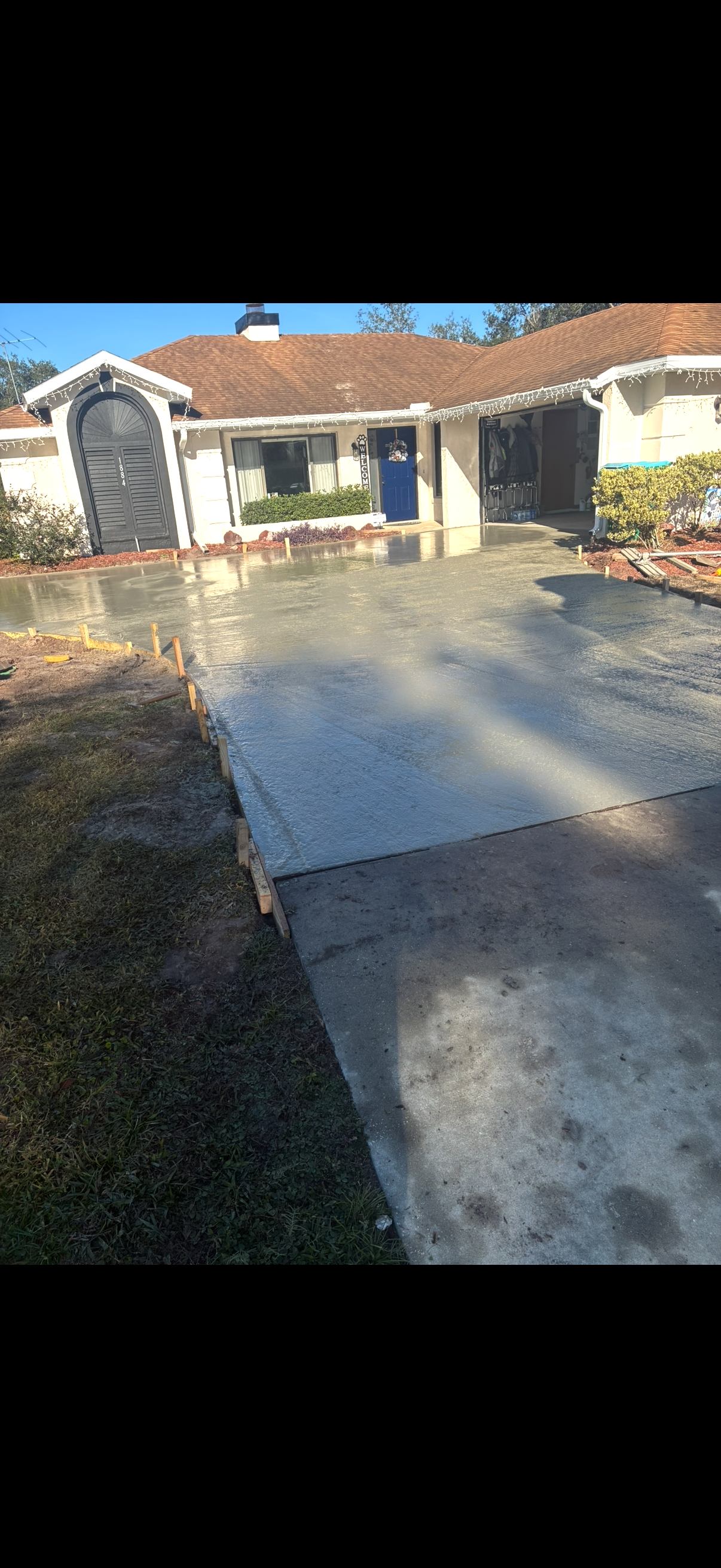 Exterior view of a house with a concrete driveway, lawn, and blue front door.