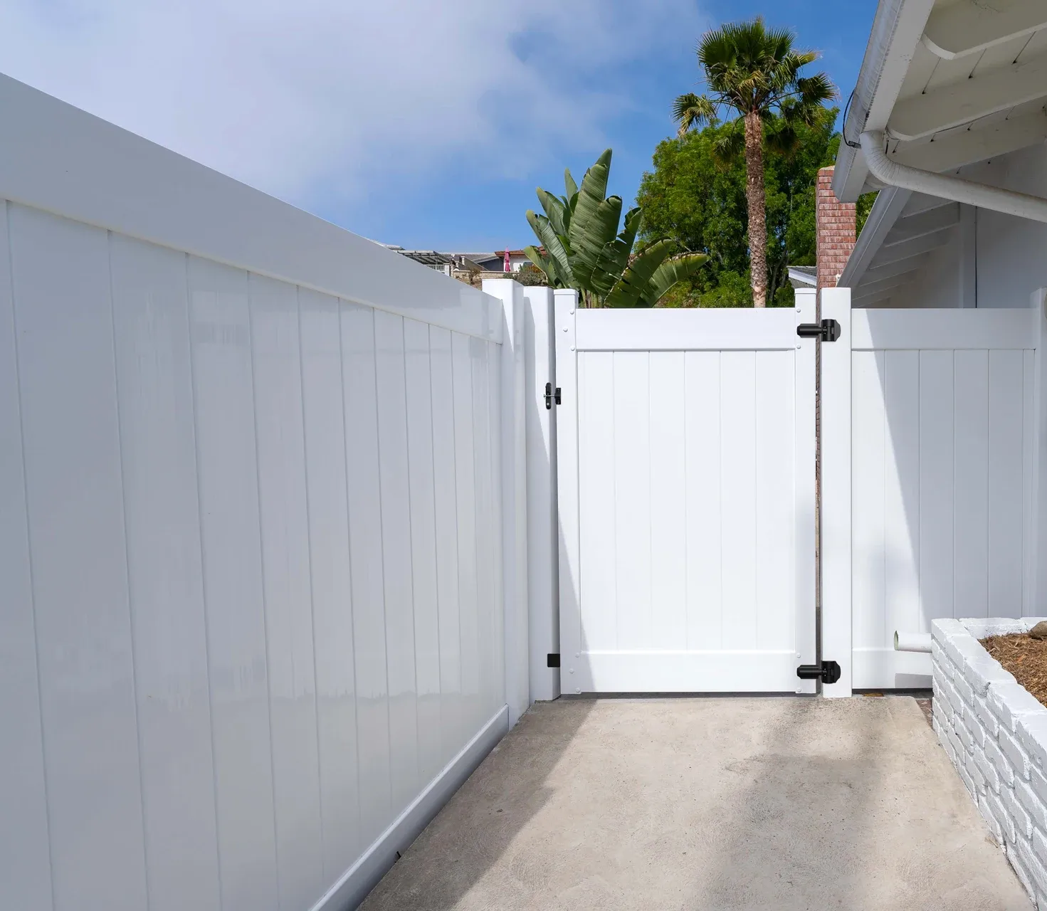 White vinyl fence with matching gate in a residential setting.