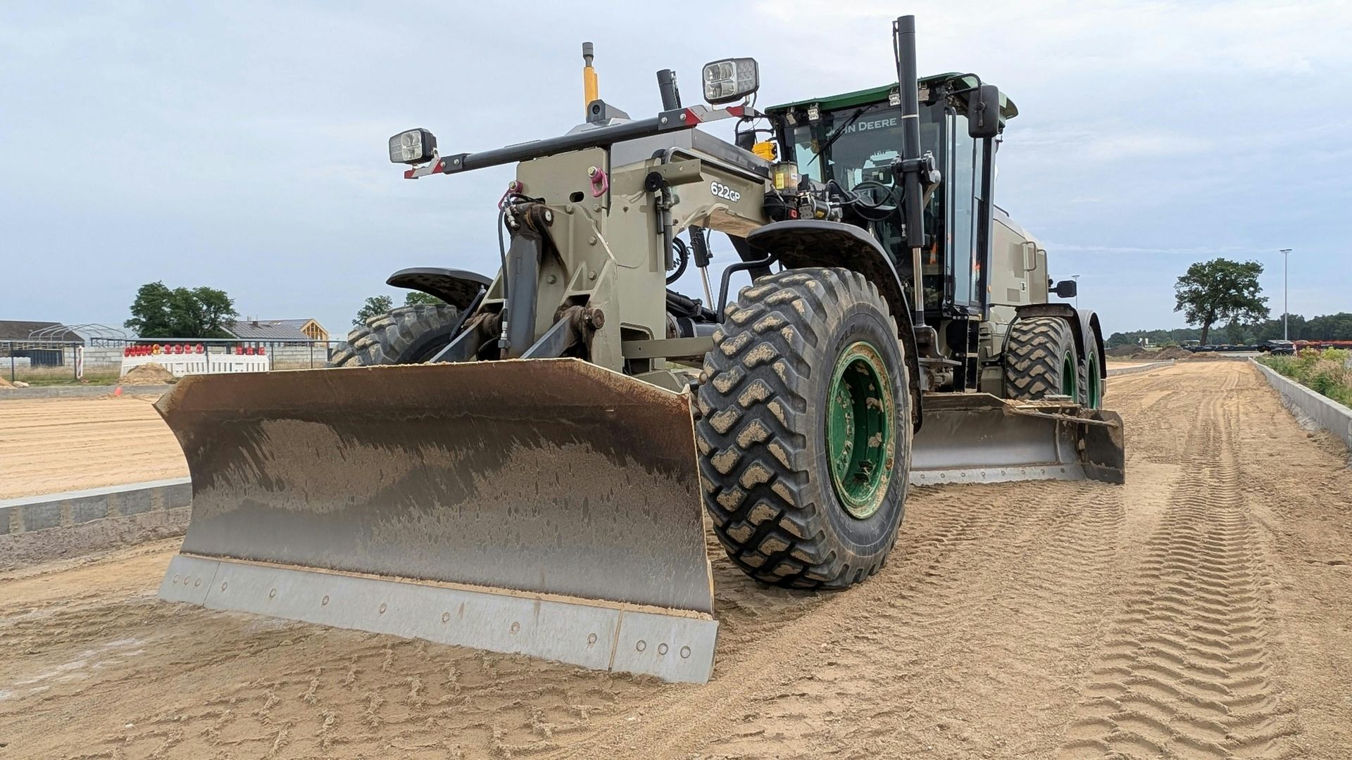 Motor grader leveling sand at a construction site.
