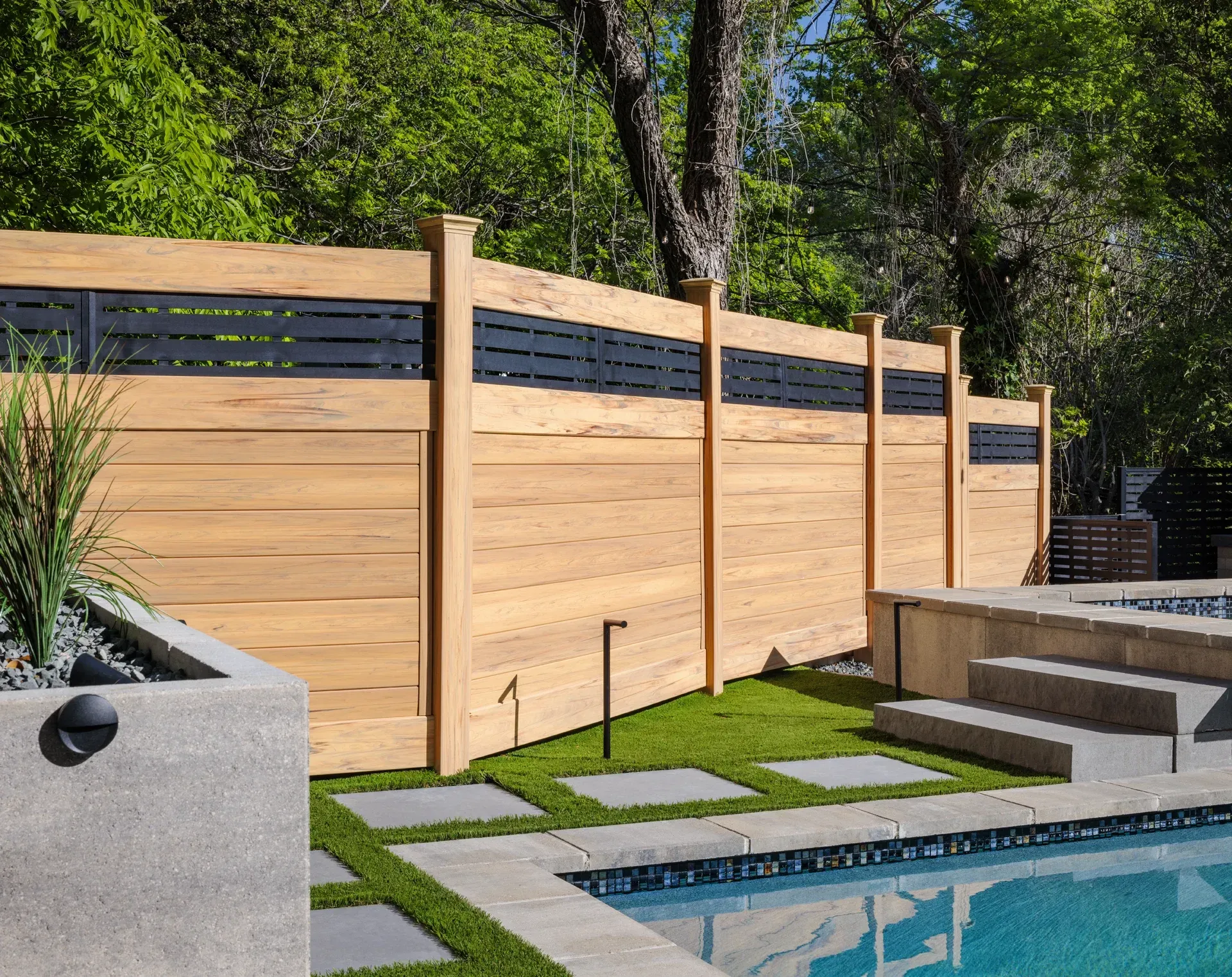 Wooden fence with black accents in a backyard near a pool.