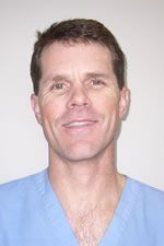 A smiling doctor in a lab coat with a stethoscope around his neck.