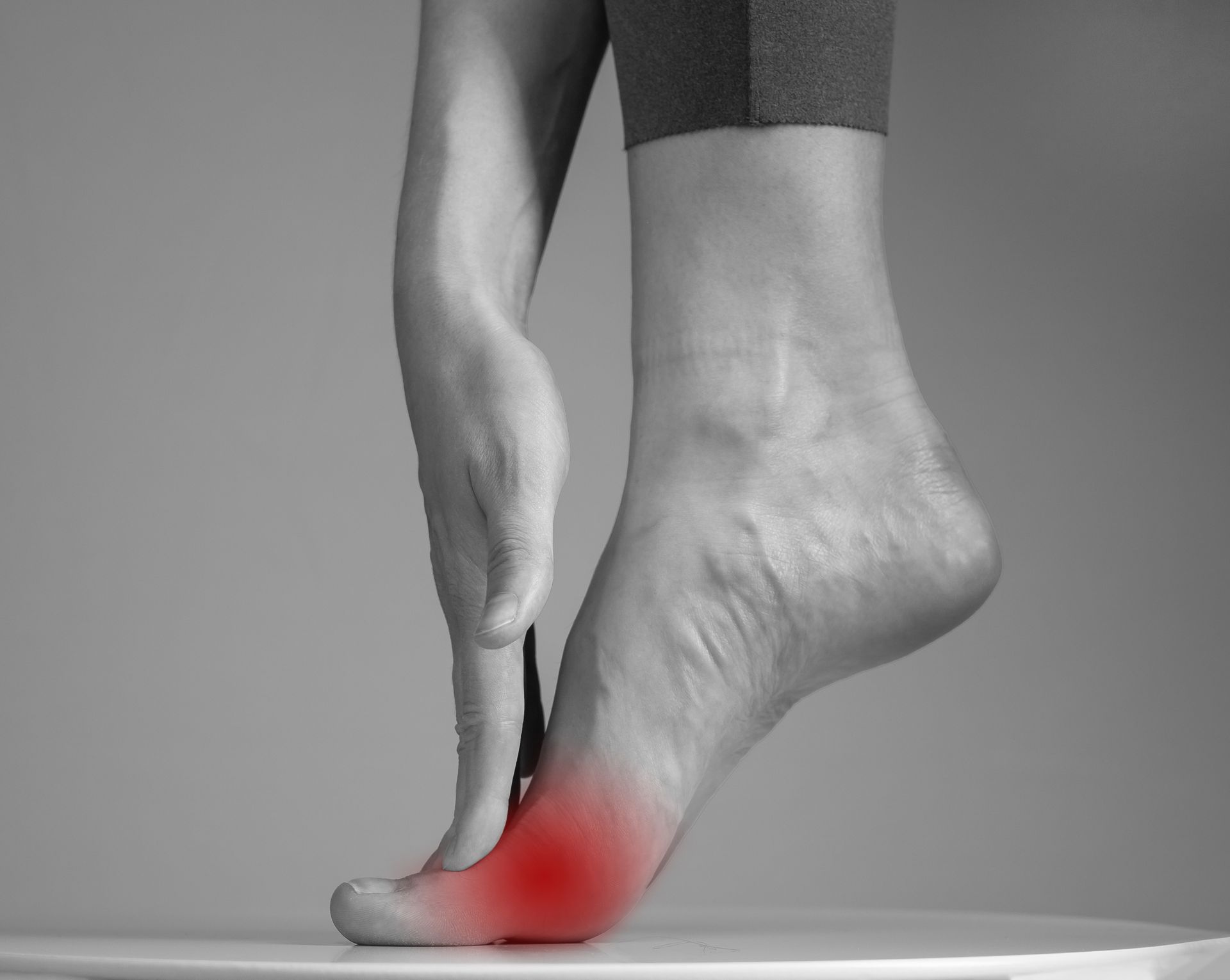 Foot in pointe position with red highlighting pain on the big toe.