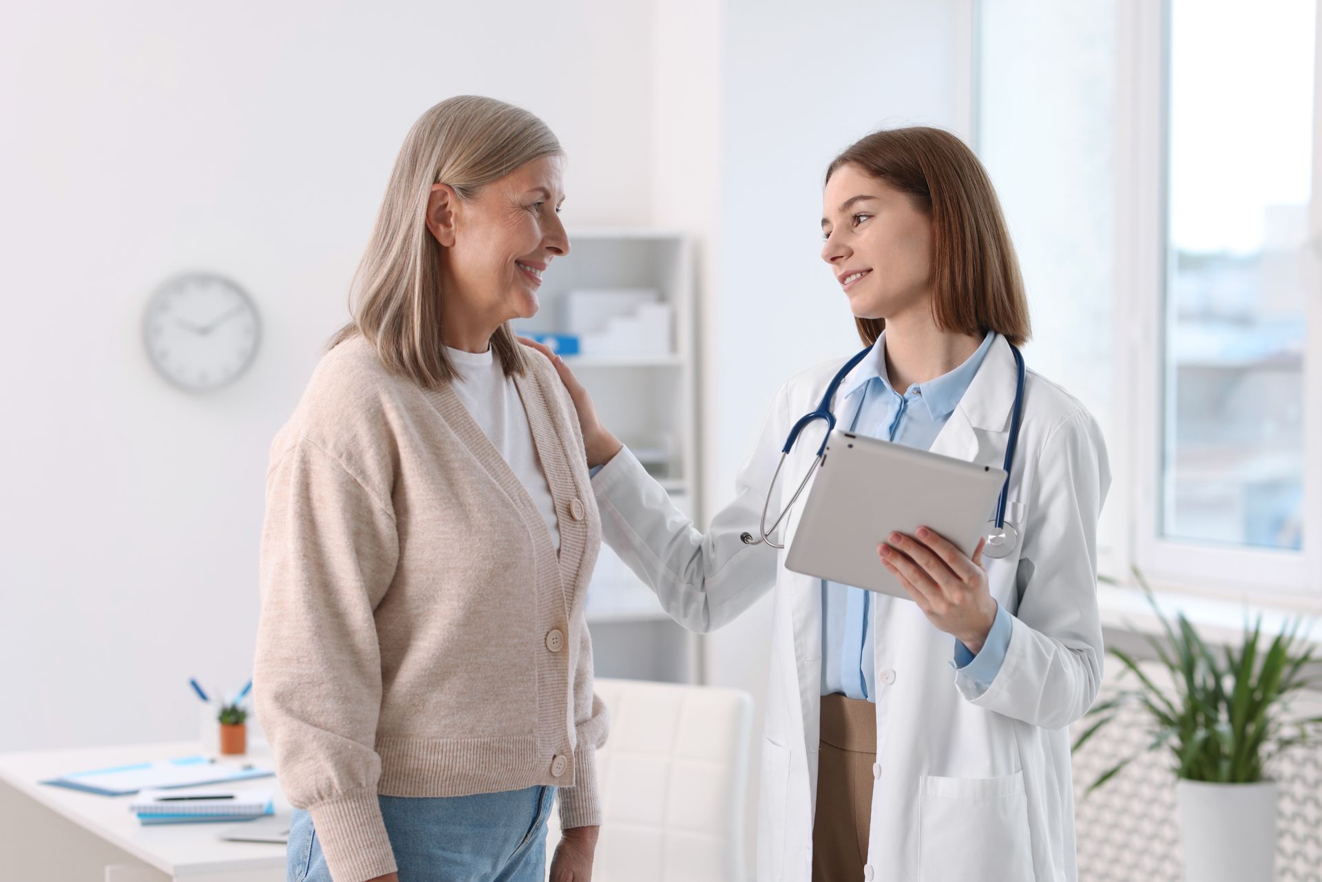 A doctor is standing next to an elderly woman in a wheelchair.
