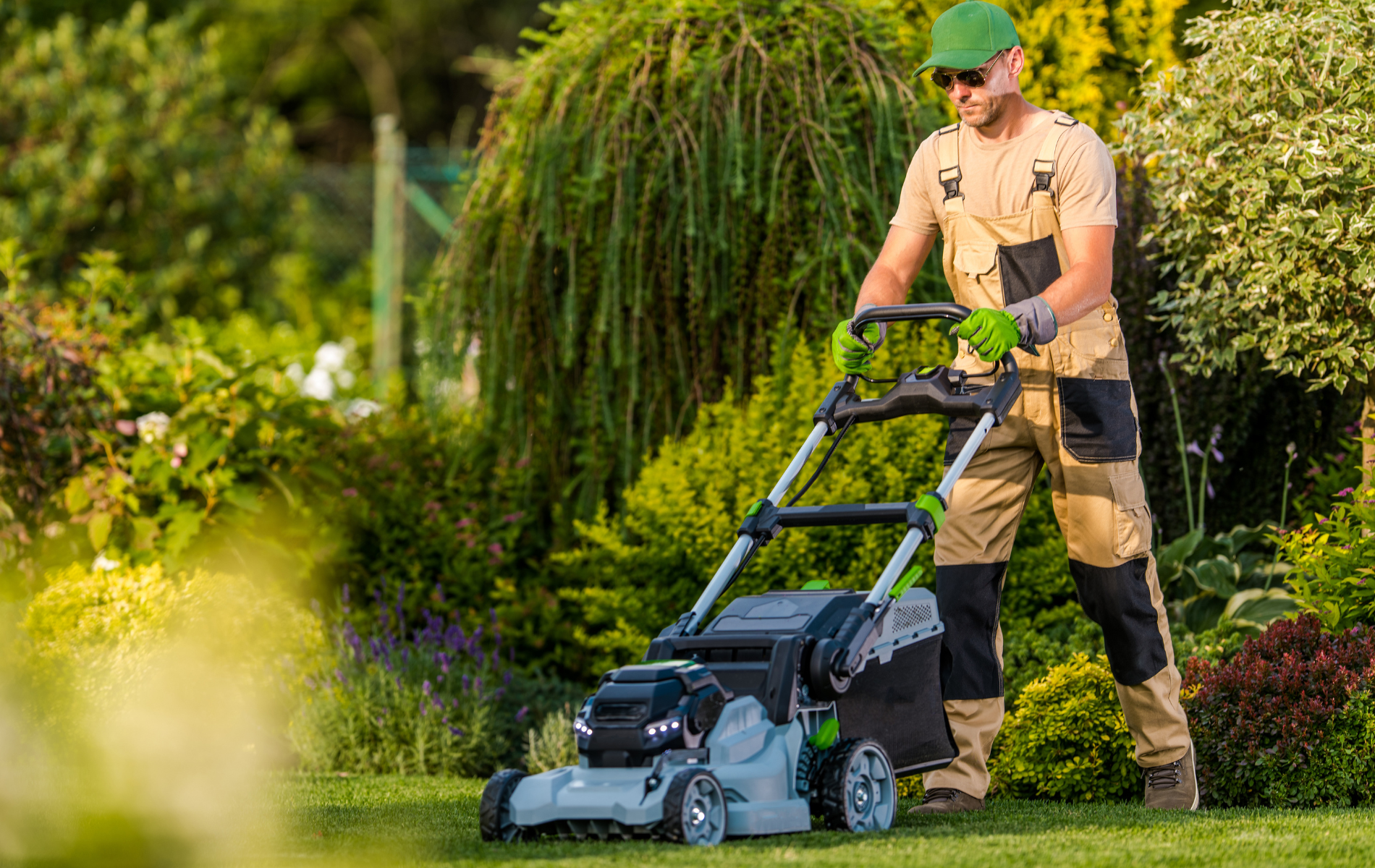 Person mowing a lawn with a push mower in a green garden
