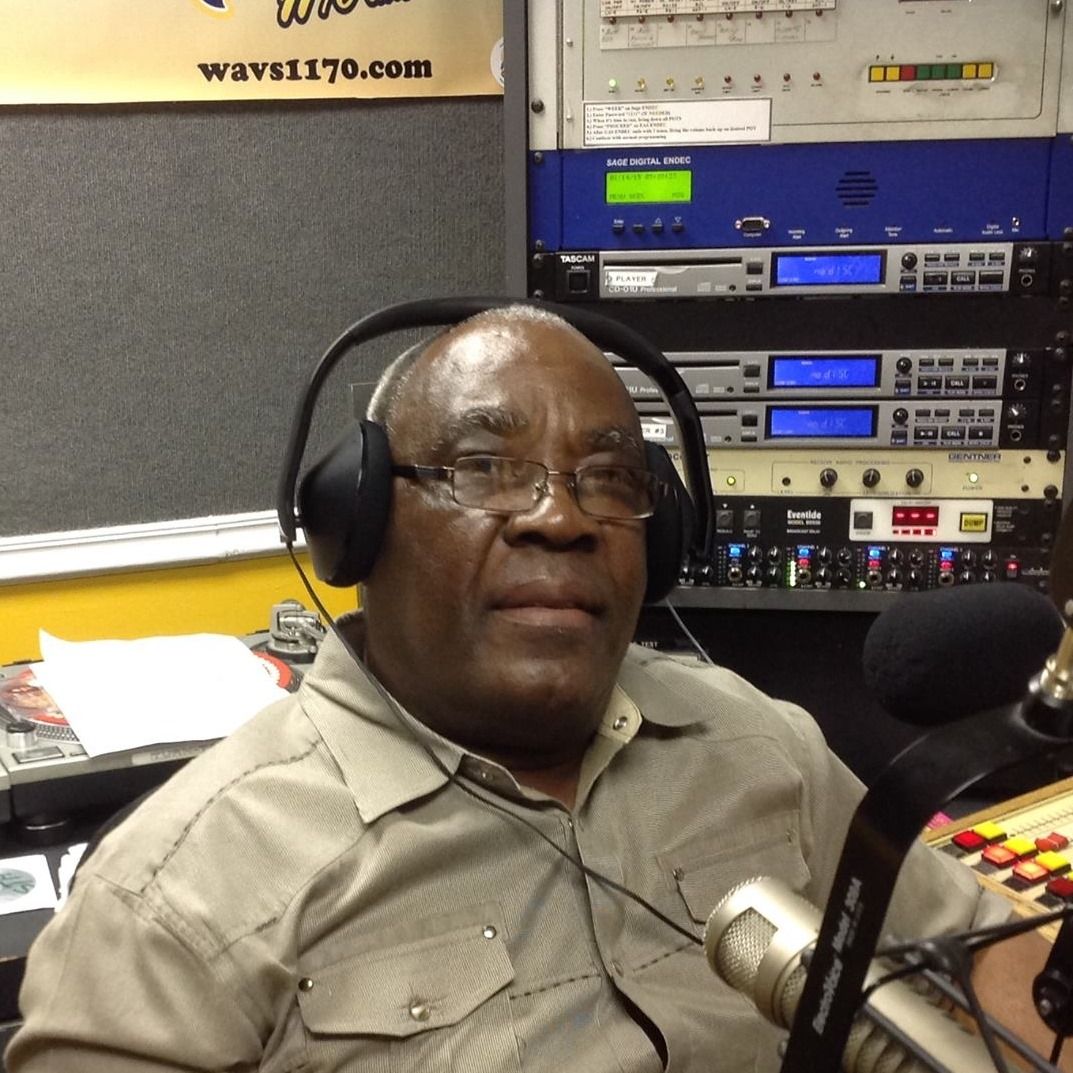 Man wearing headphones at radio station, microphone in front.