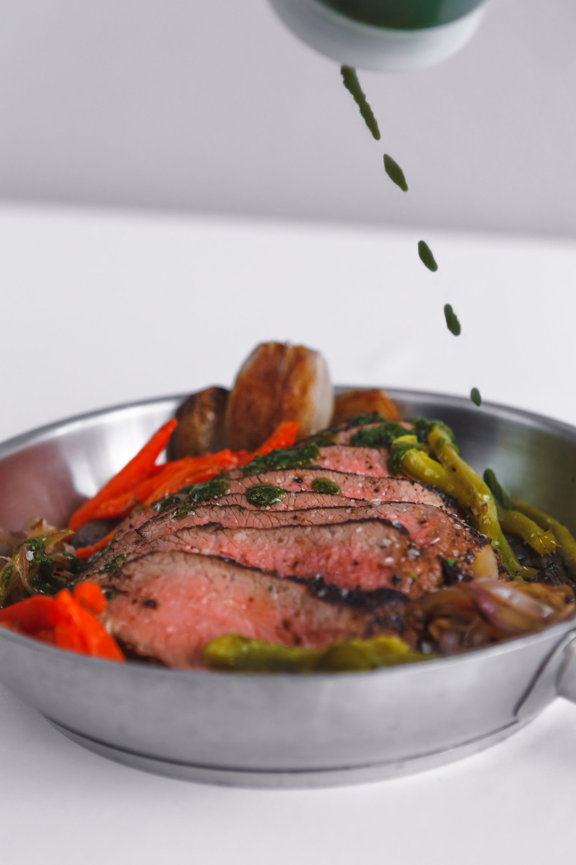 A close up of a plate of food with meat and vegetables on a table.