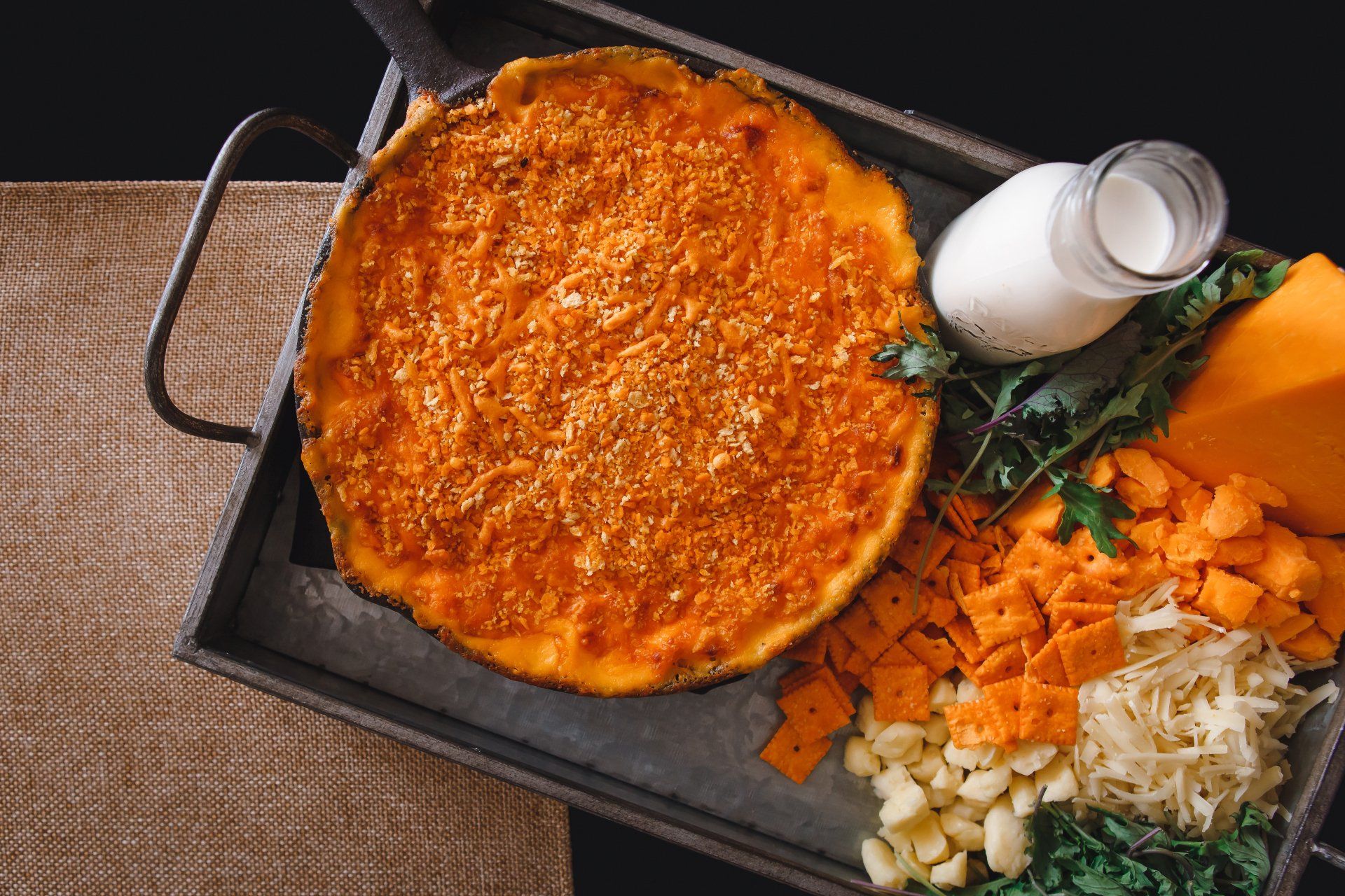 There is a pizza on a tray with vegetables and a bottle of milk.