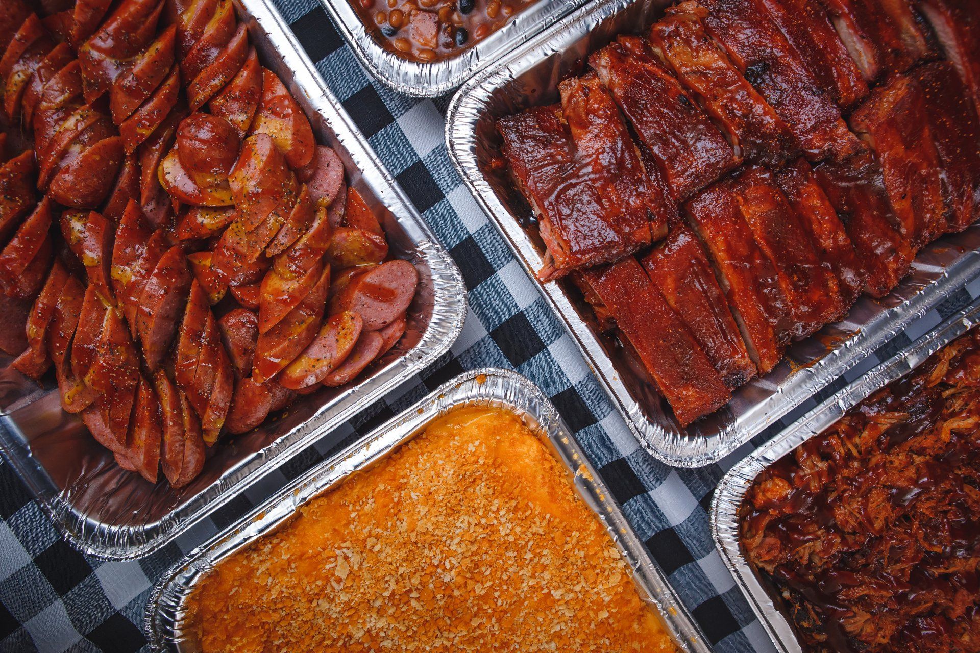 There are many different types of food in foil containers on the table.