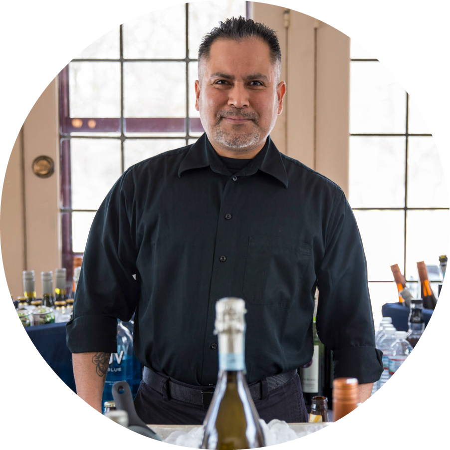 A man in a black shirt is standing in front of a bottle of wine