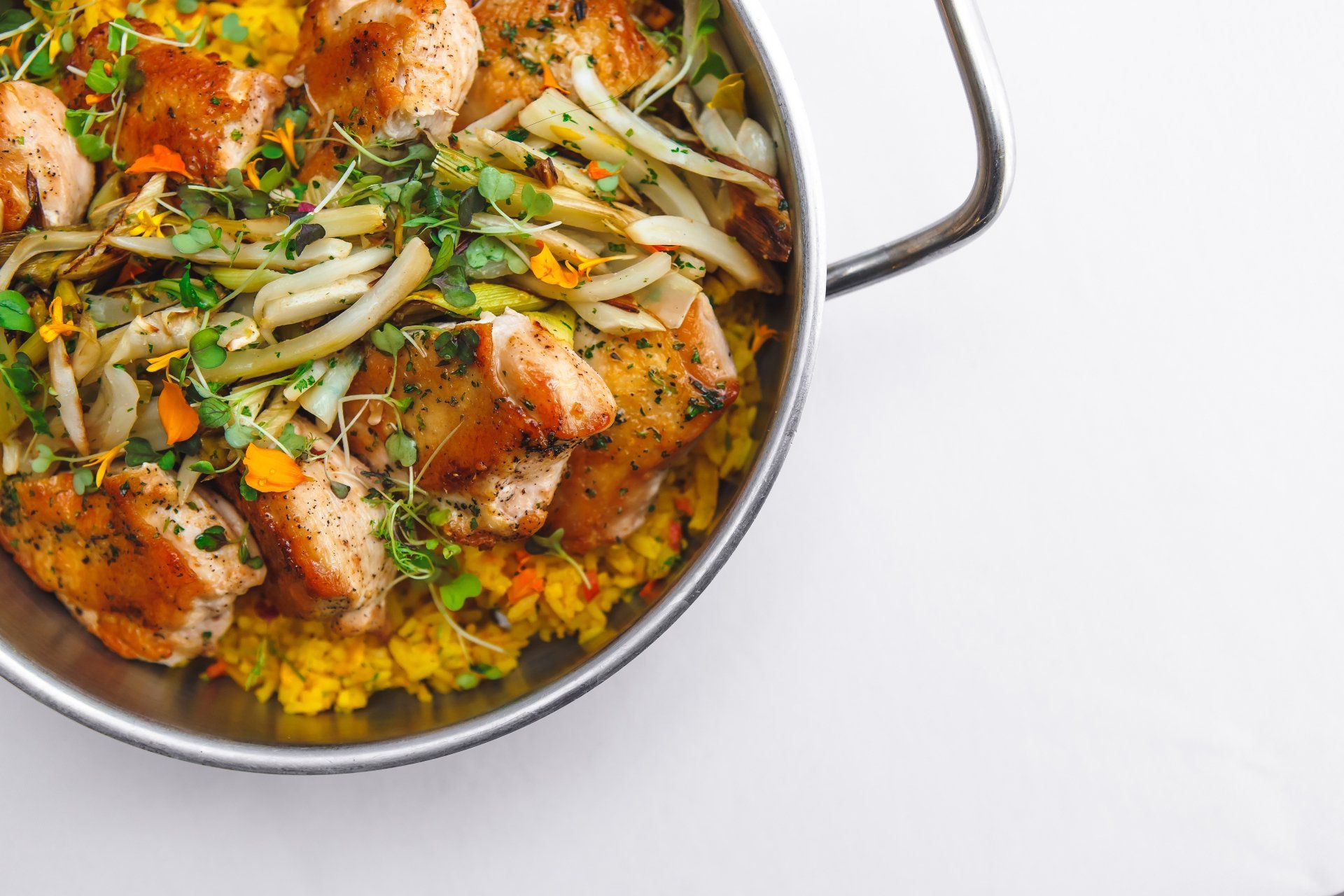 A pan filled with rice , meat and vegetables on a table.